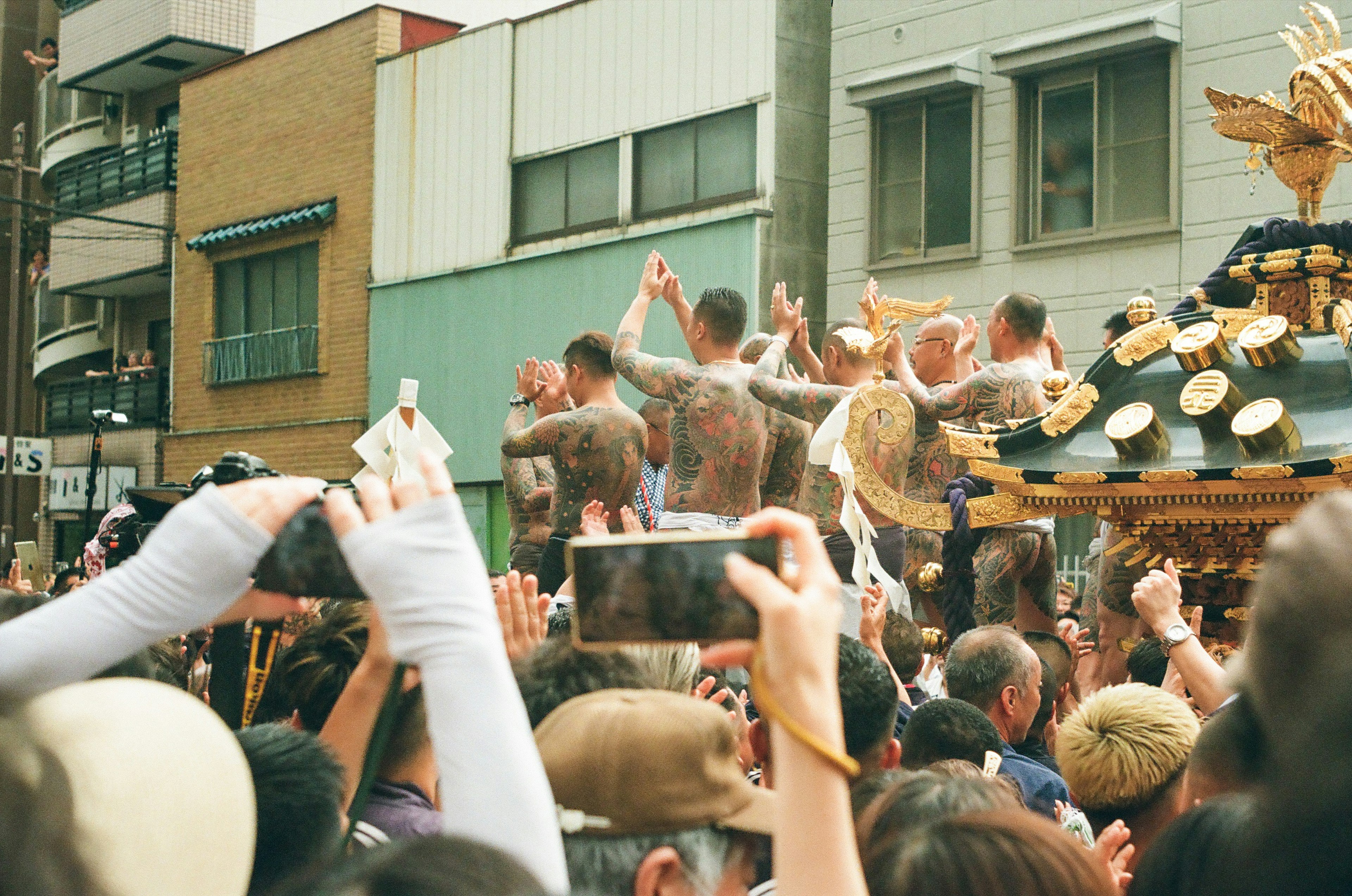 Festival participants carrying a portable shrine with many spectators taking photos