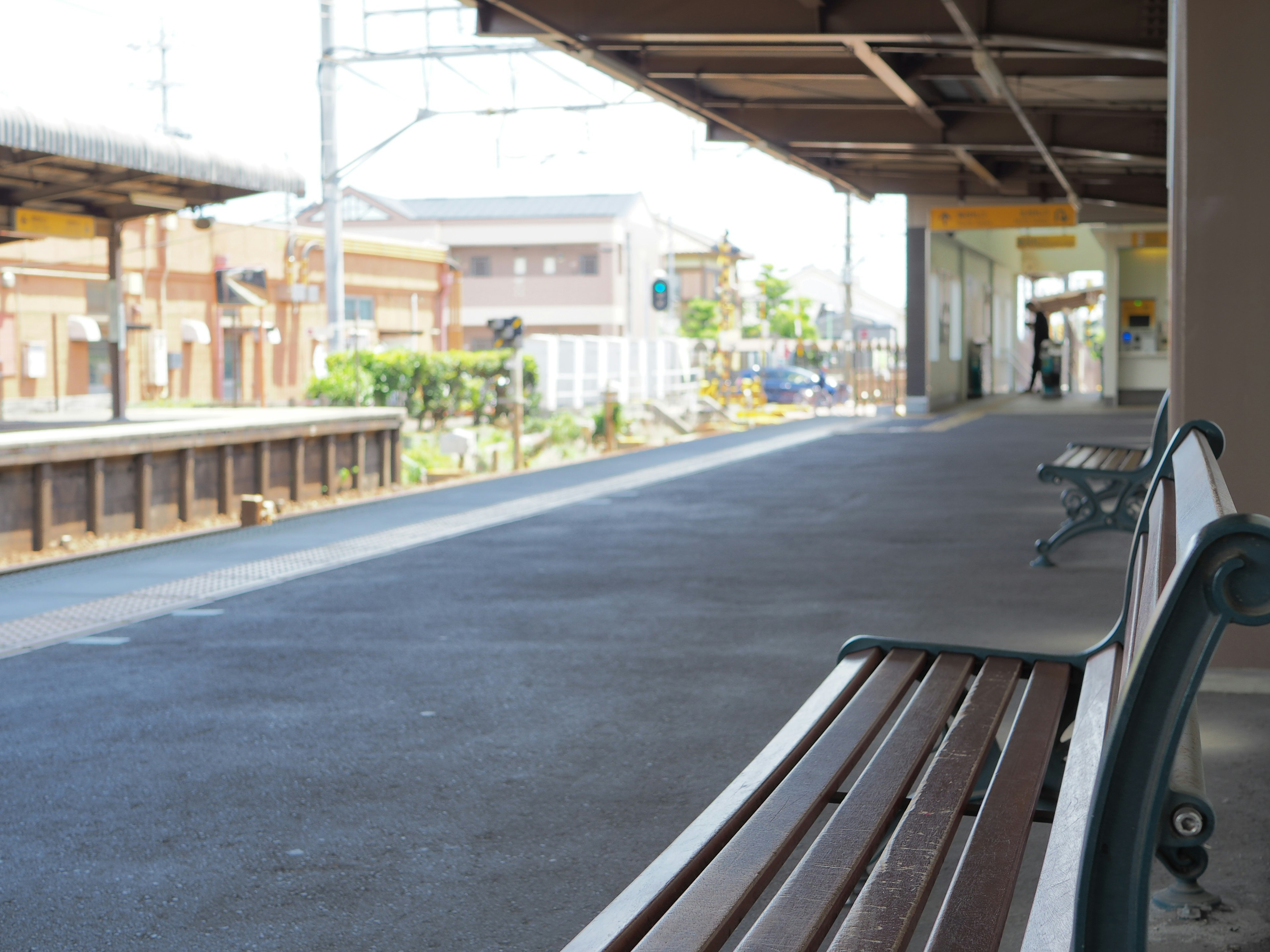 Bangku kayu di platform stasiun kereta yang tenang dengan pemandangan sekitar