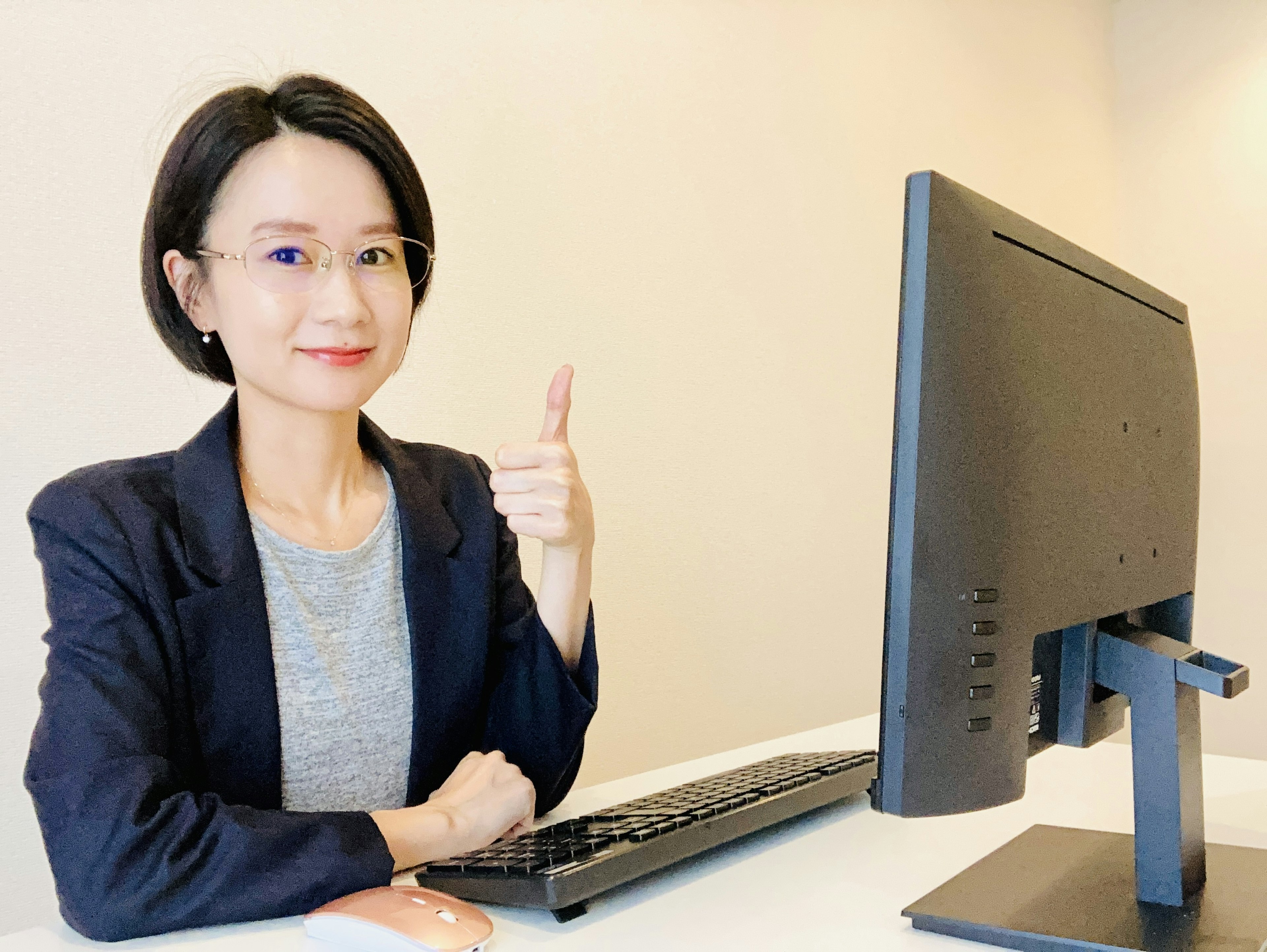 Woman in business suit giving thumbs up in front of a computer