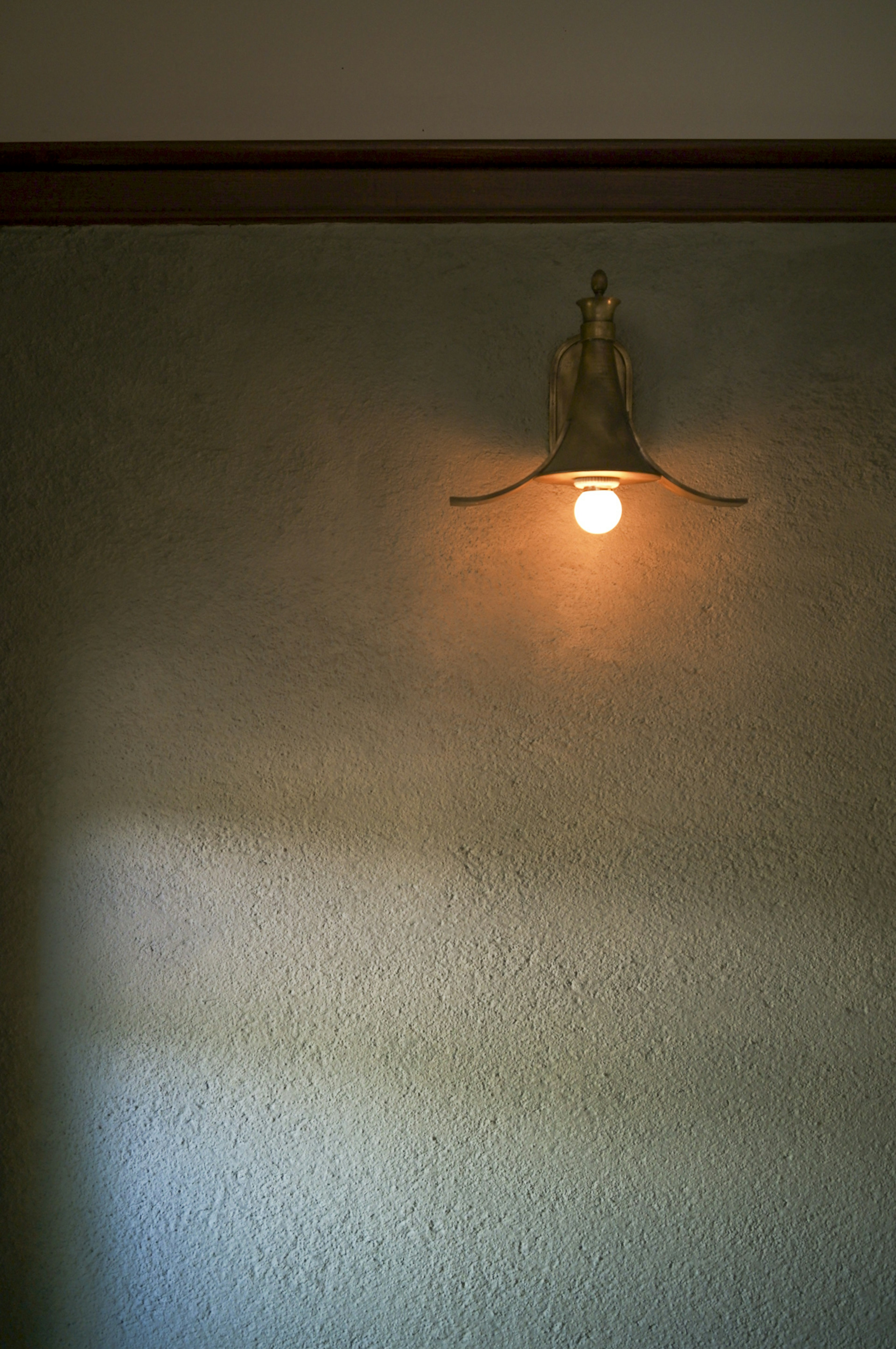 Vintage style wall-mounted lamp illuminated on a textured wall