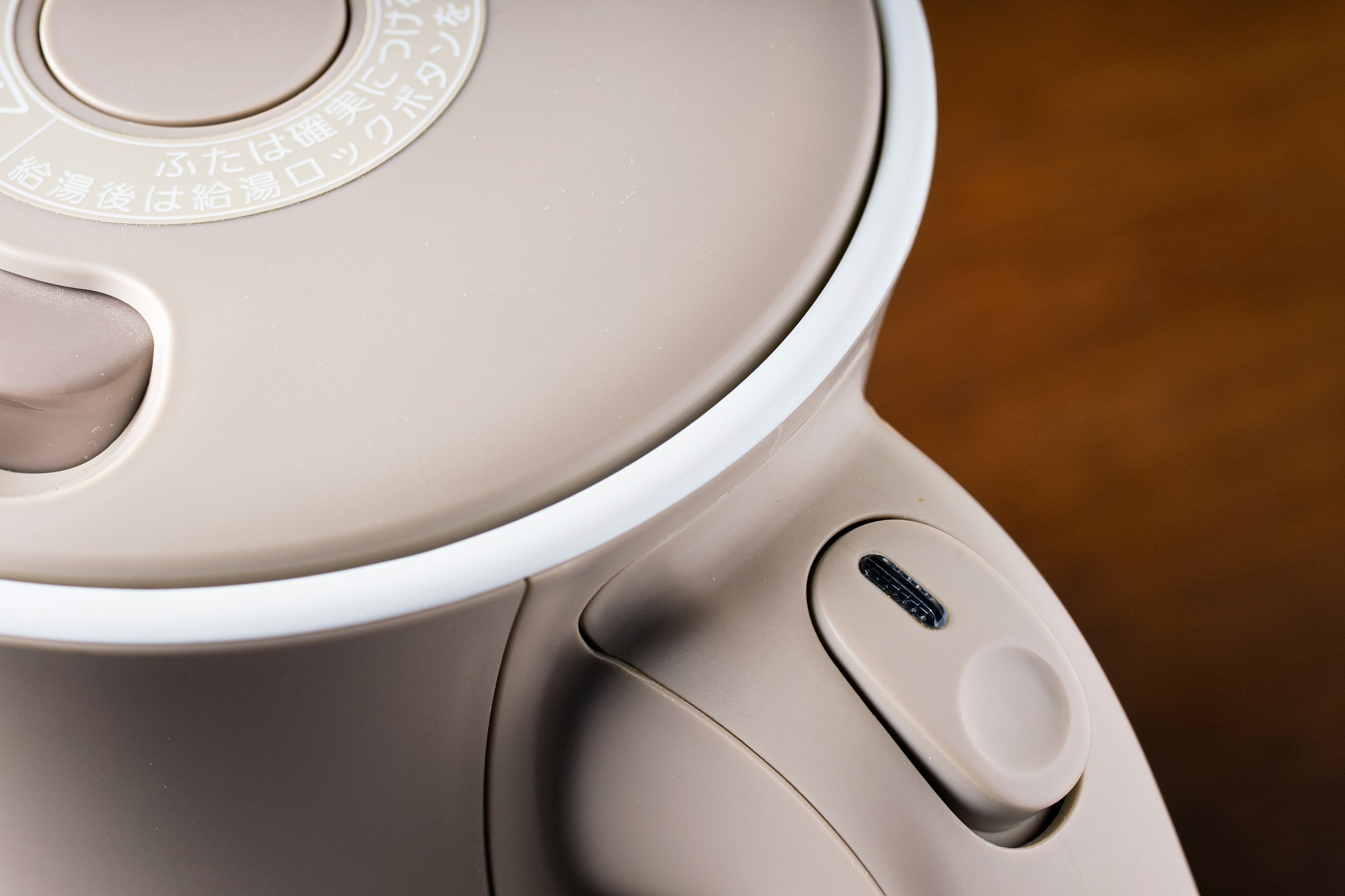 Close-up of a compact electric kettle featuring a button with LED light