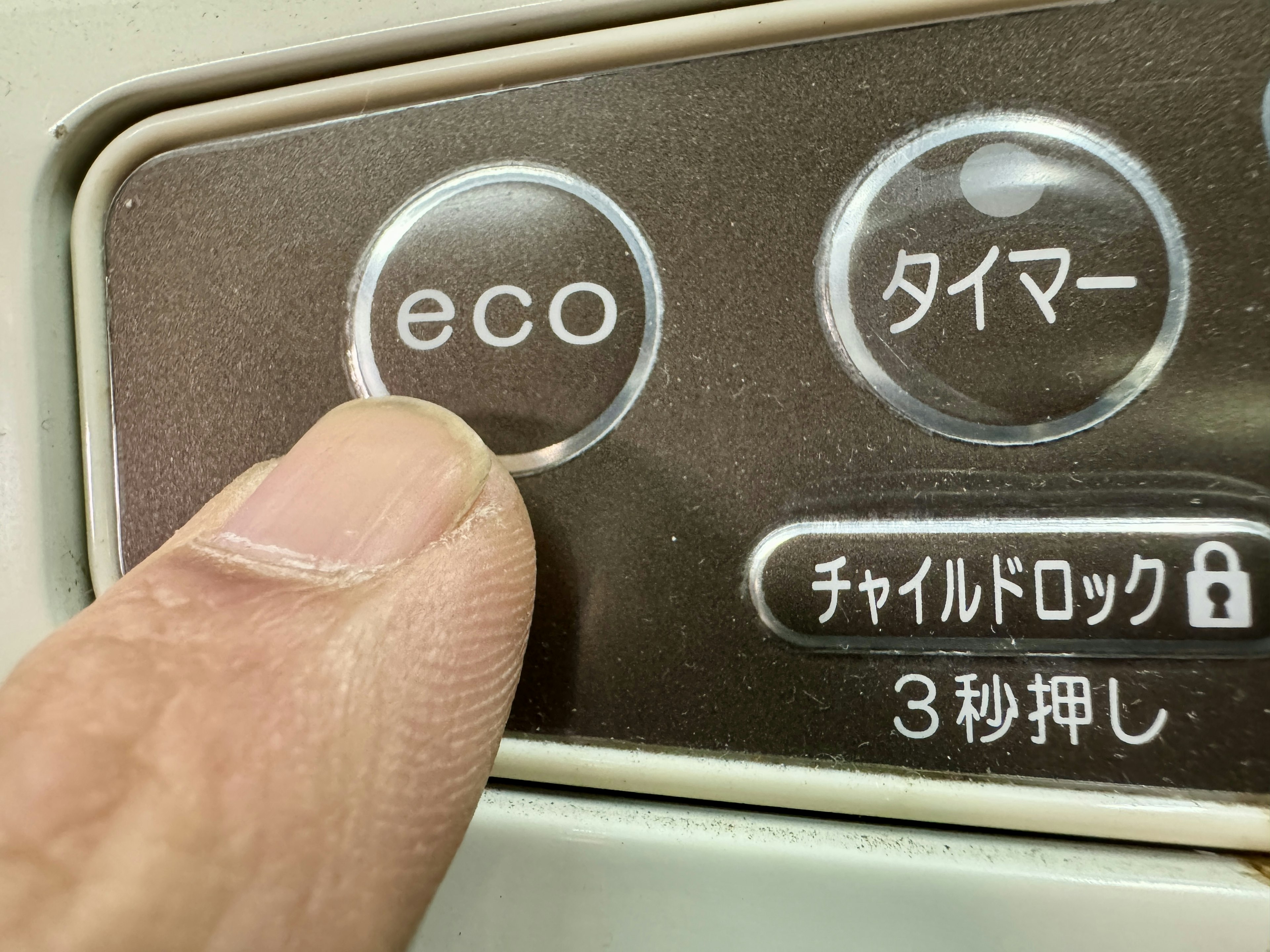 Close-up of a hand pressing the eco button