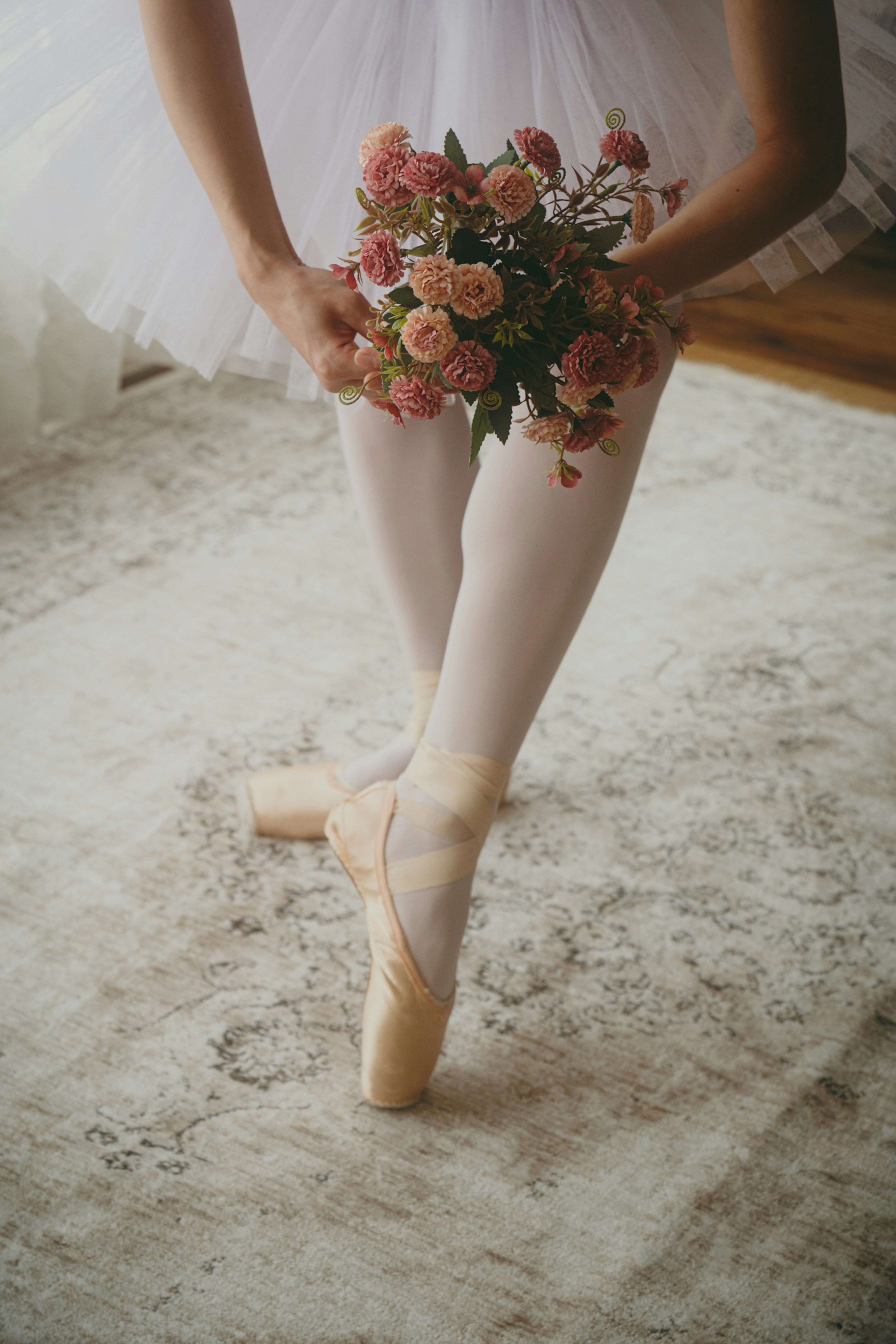 Ballerina's feet holding a bouquet in a white tutu and tights