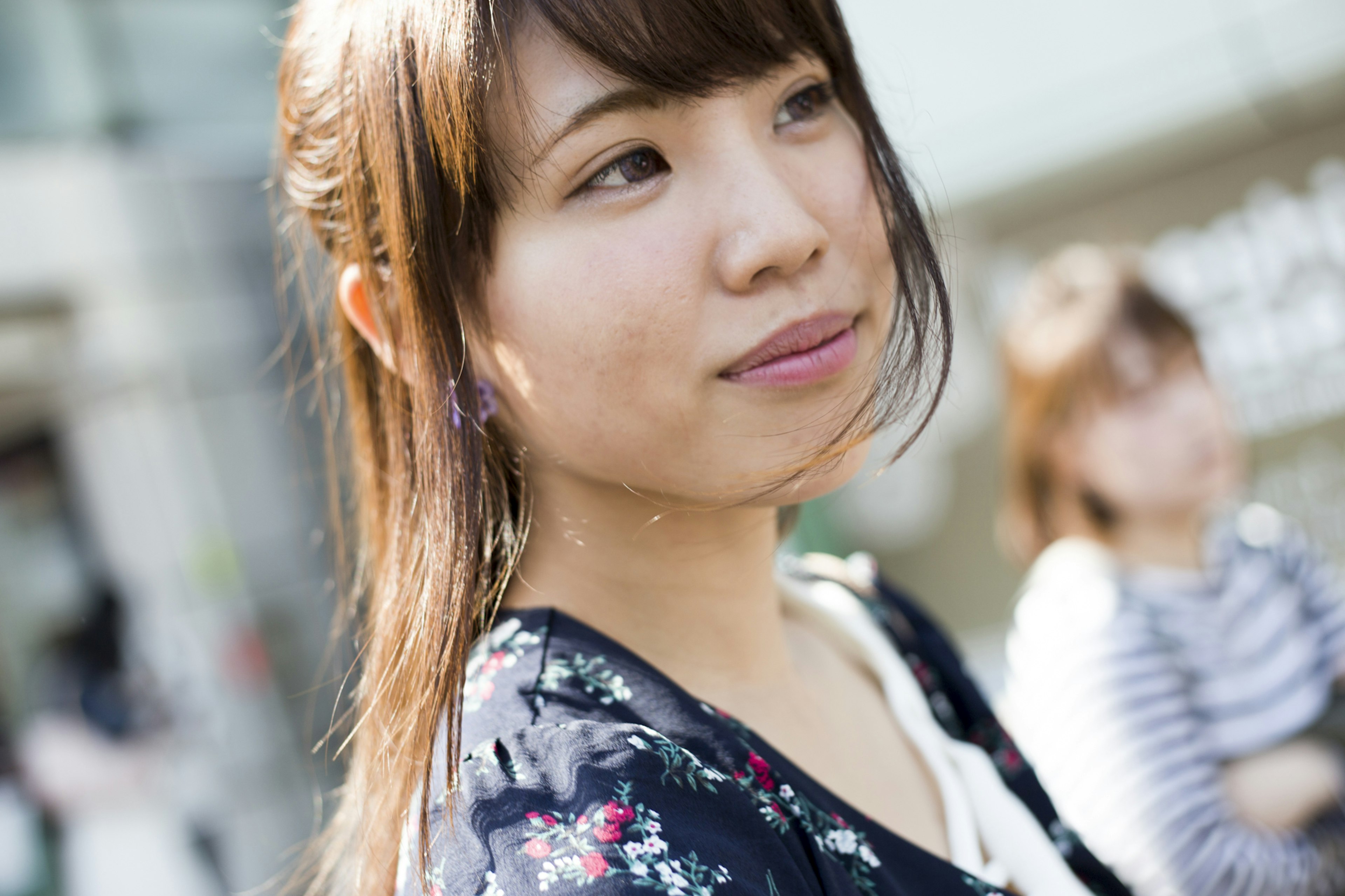 Mujer joven con atuendo floral sonriendo en un entorno urbano