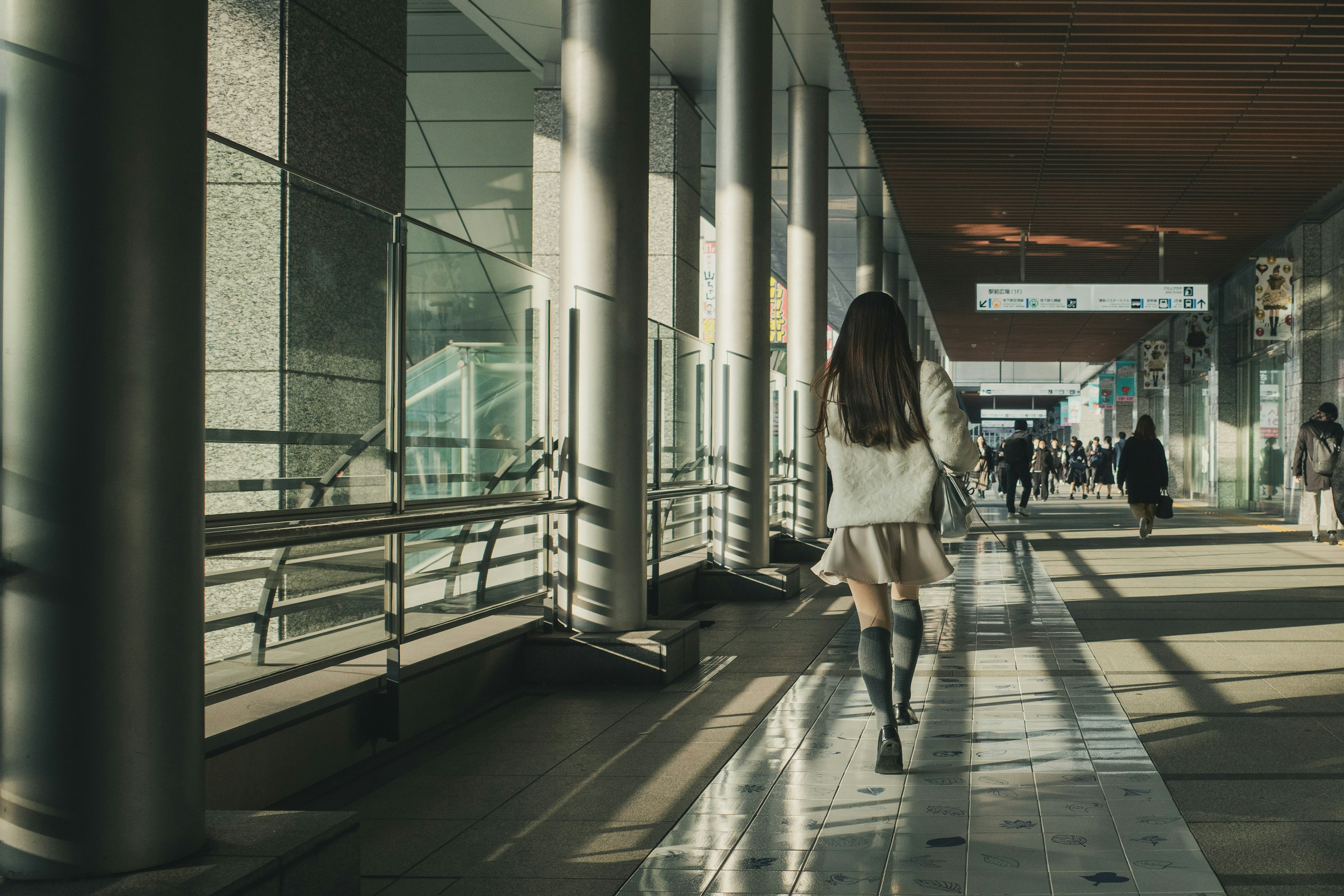 A woman walking in a spacious corridor with large windows