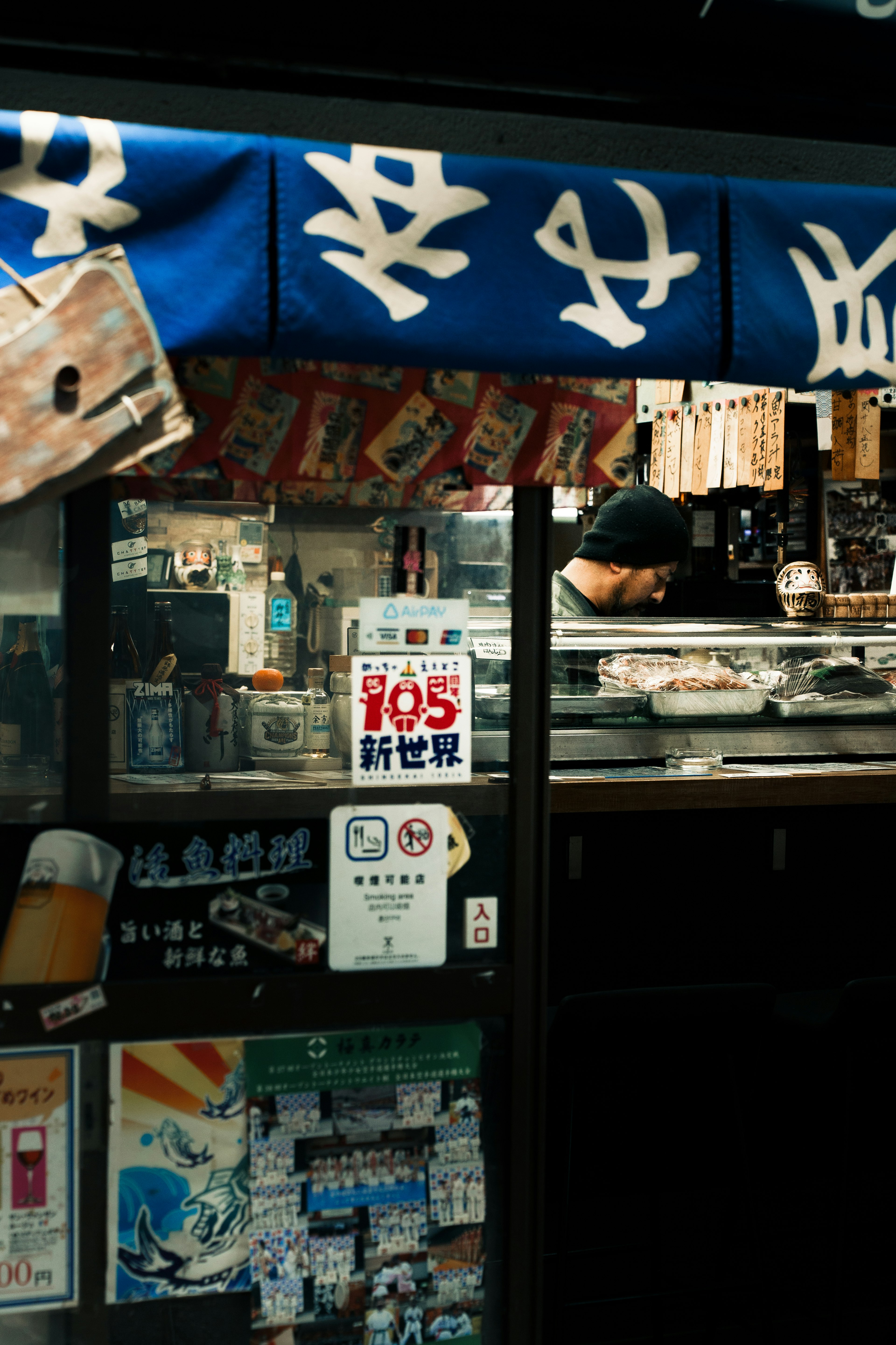 Extérieur d'un restaurant japonais sous un auvent bleu avec divers panneaux et menus