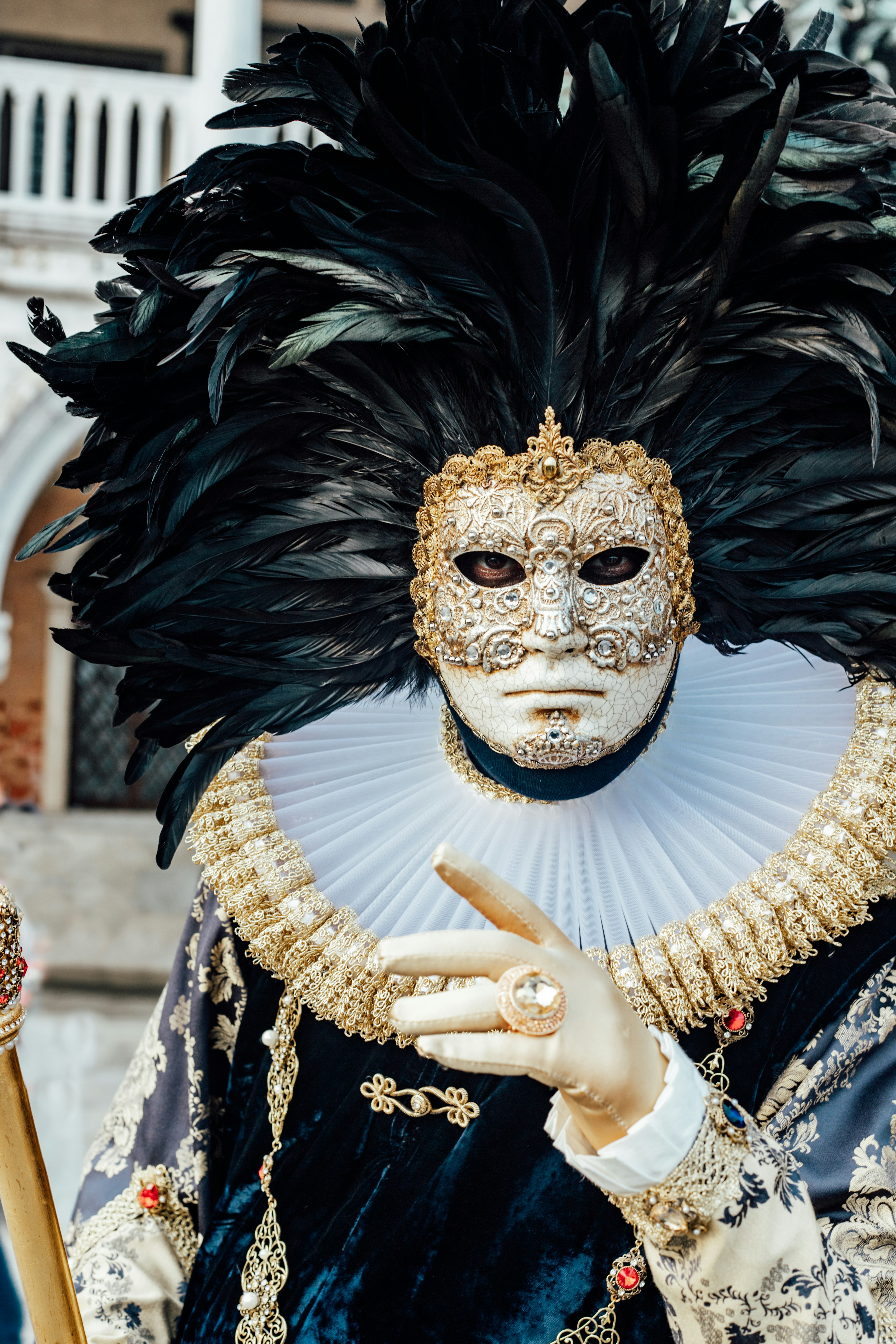 A person wearing an ornate mask and elaborate feathered headdress