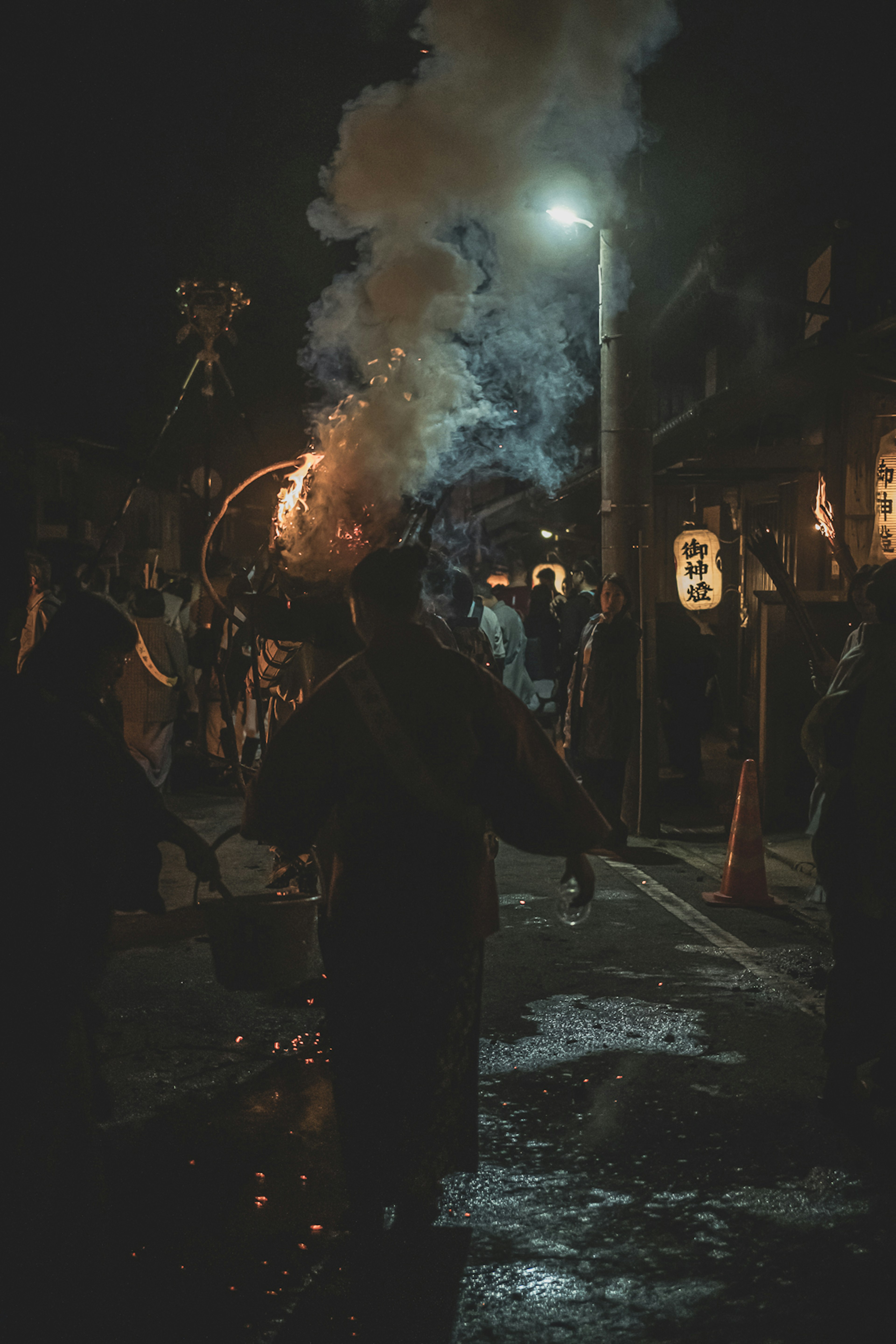 Silhouetten von Personen, die Feuer halten, das Rauch während eines Nachtfestes abgibt