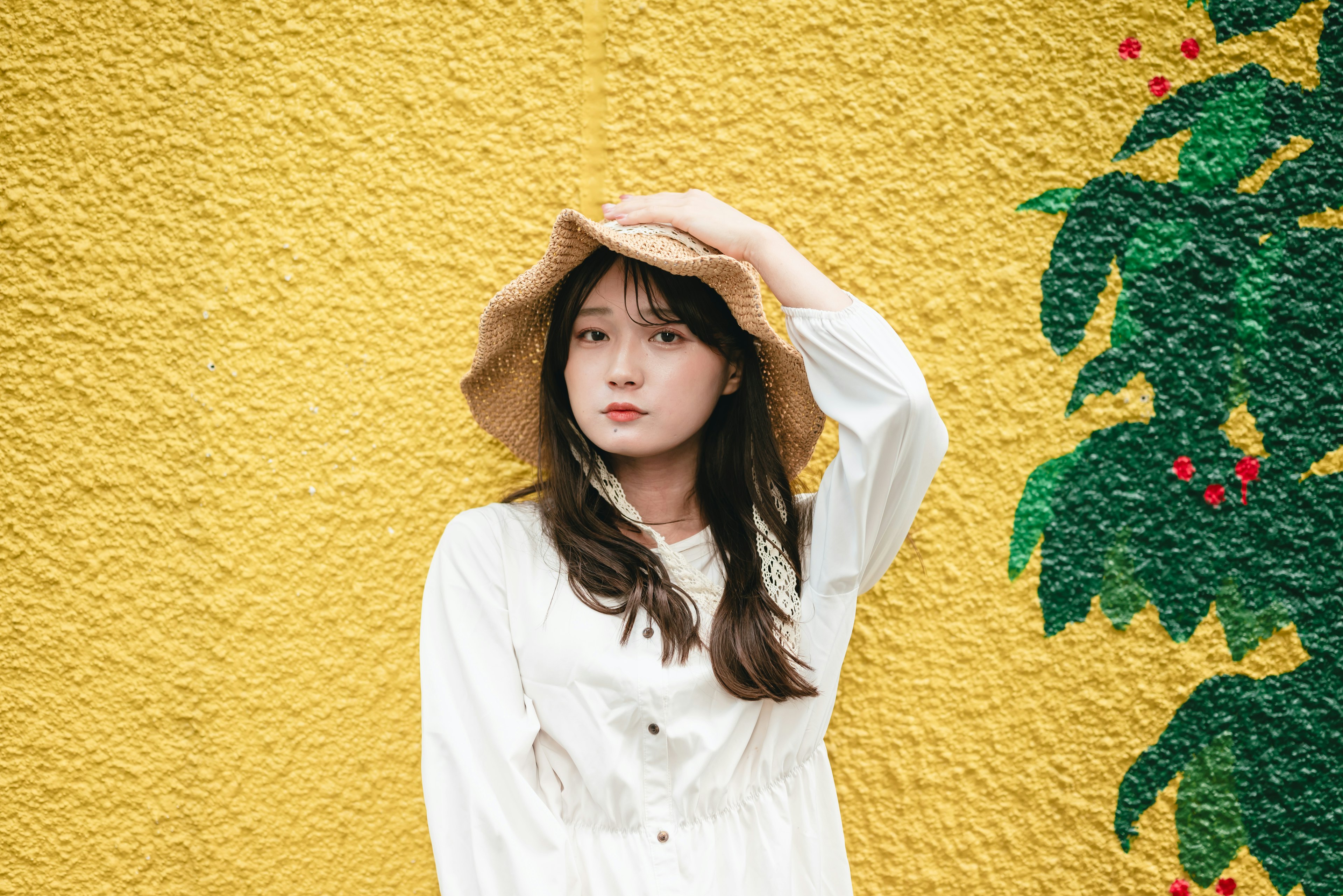 Woman in a white dress standing in front of a yellow wall