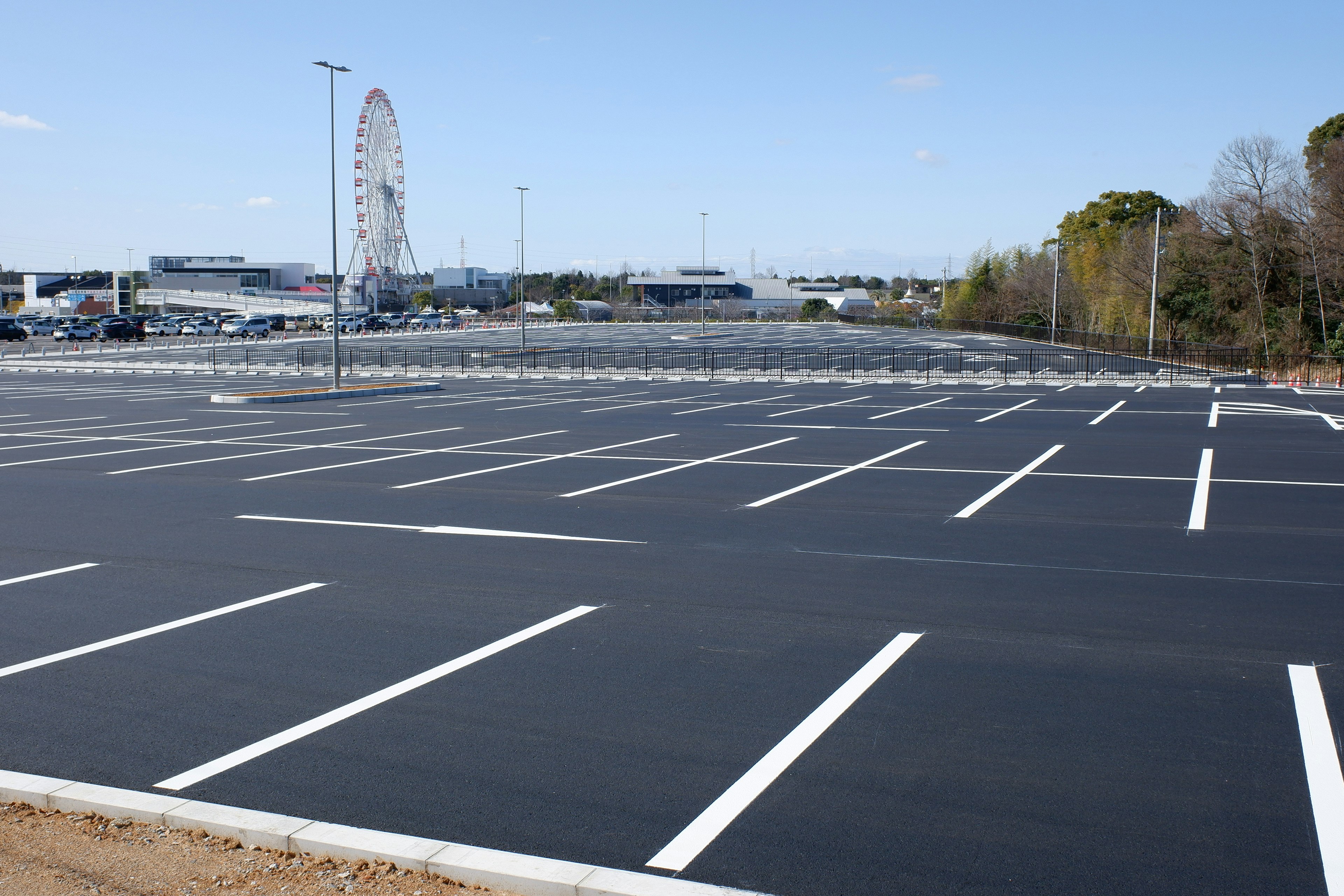 Großer Parkplatz mit sichtbarem Riesenrad unter blauem Himmel