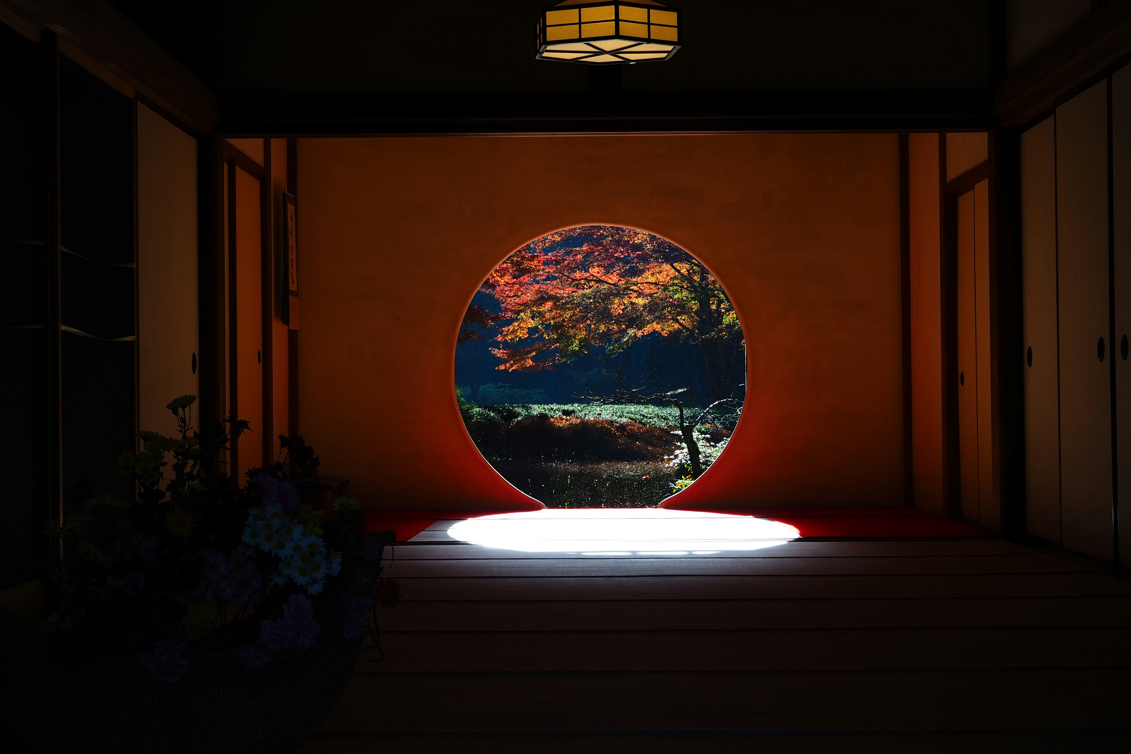 Interior of a Japanese room featuring a circular window showcasing a beautiful landscape