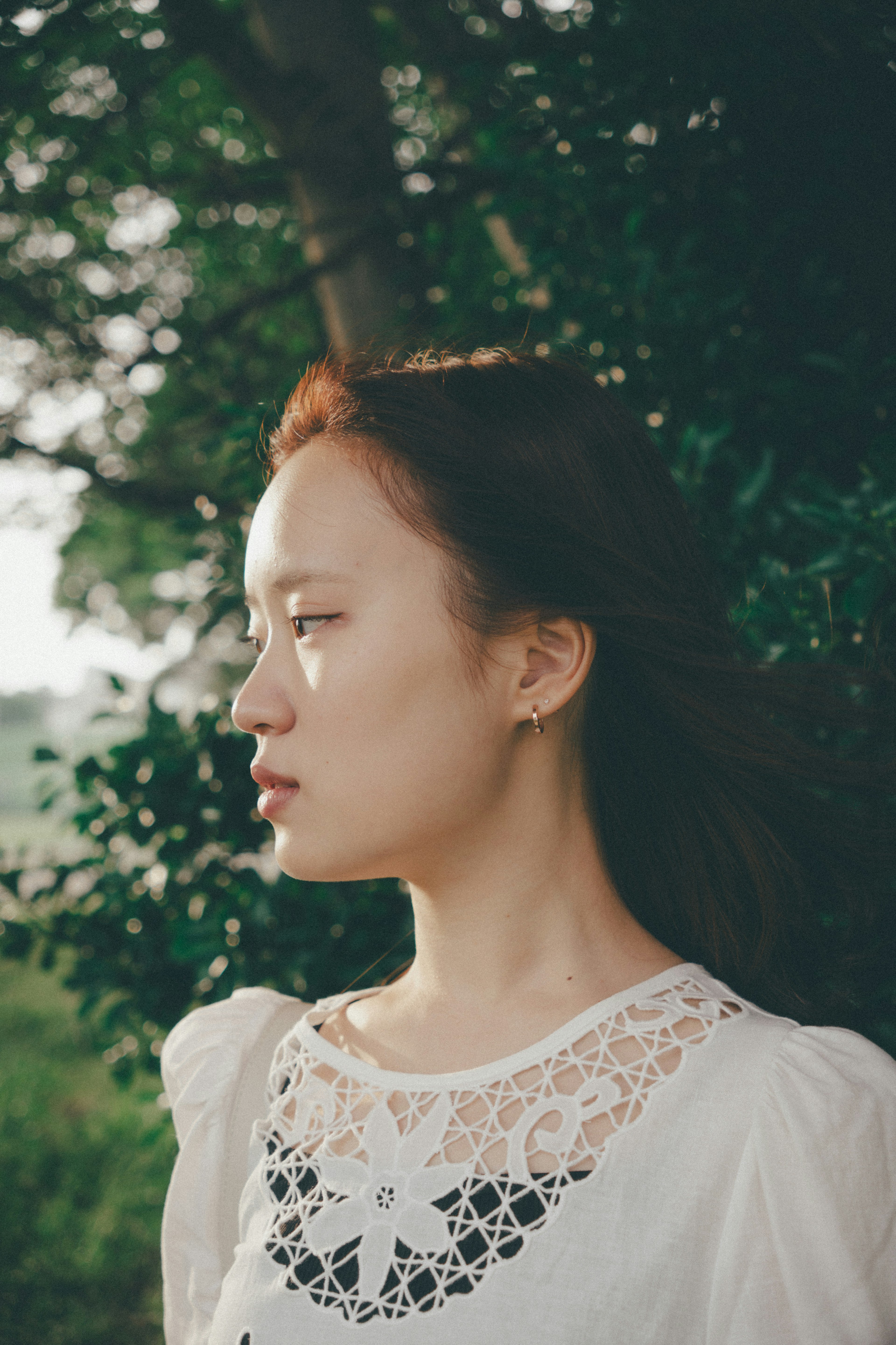 Retrato de perfil de una mujer en la naturaleza con una blusa de encaje blanco