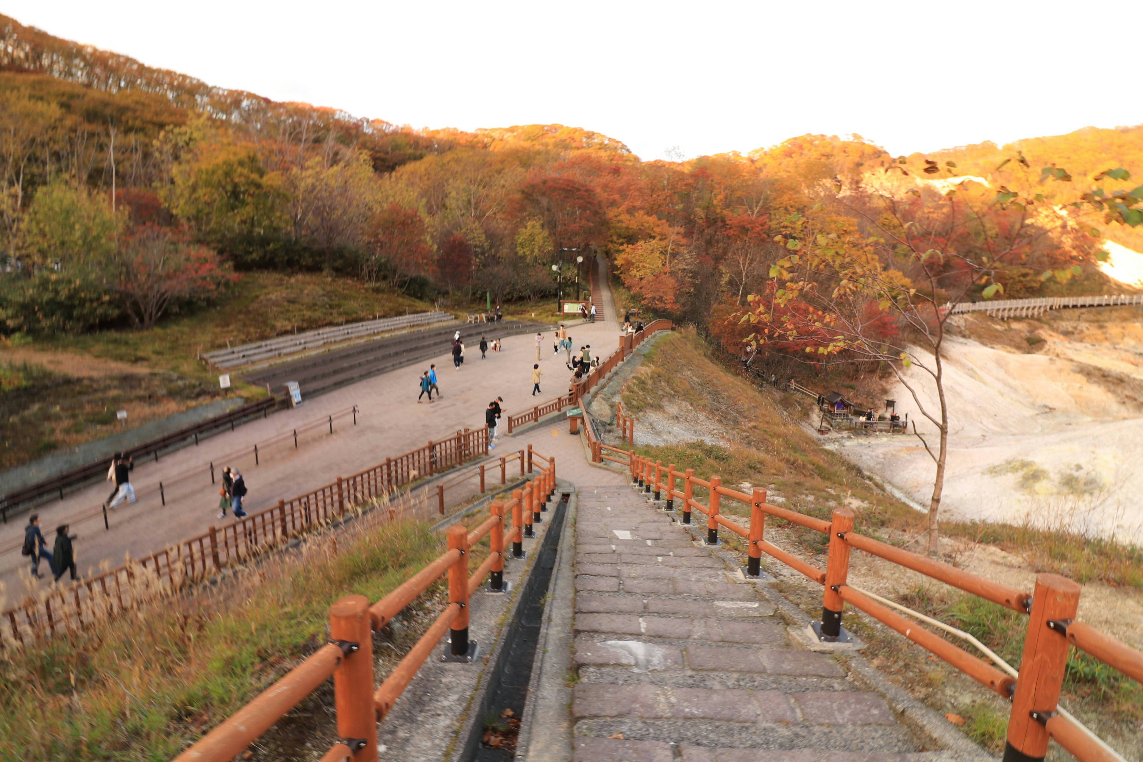 Staircase leading to a scenic area with people walking in autumn foliage