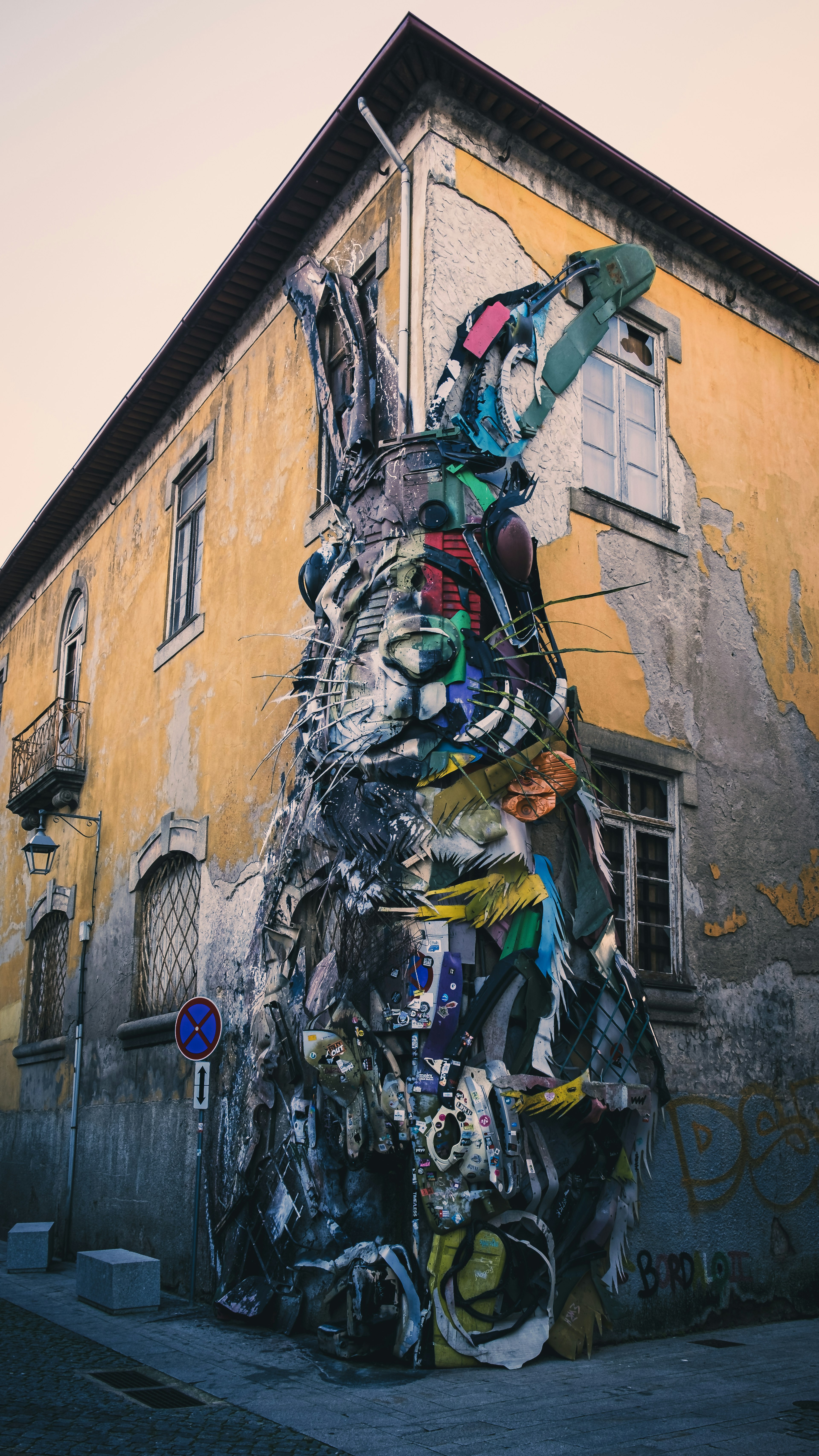 Installation artistique colorée faite de matériaux recyclés recouvrant un mur d'un vieux bâtiment