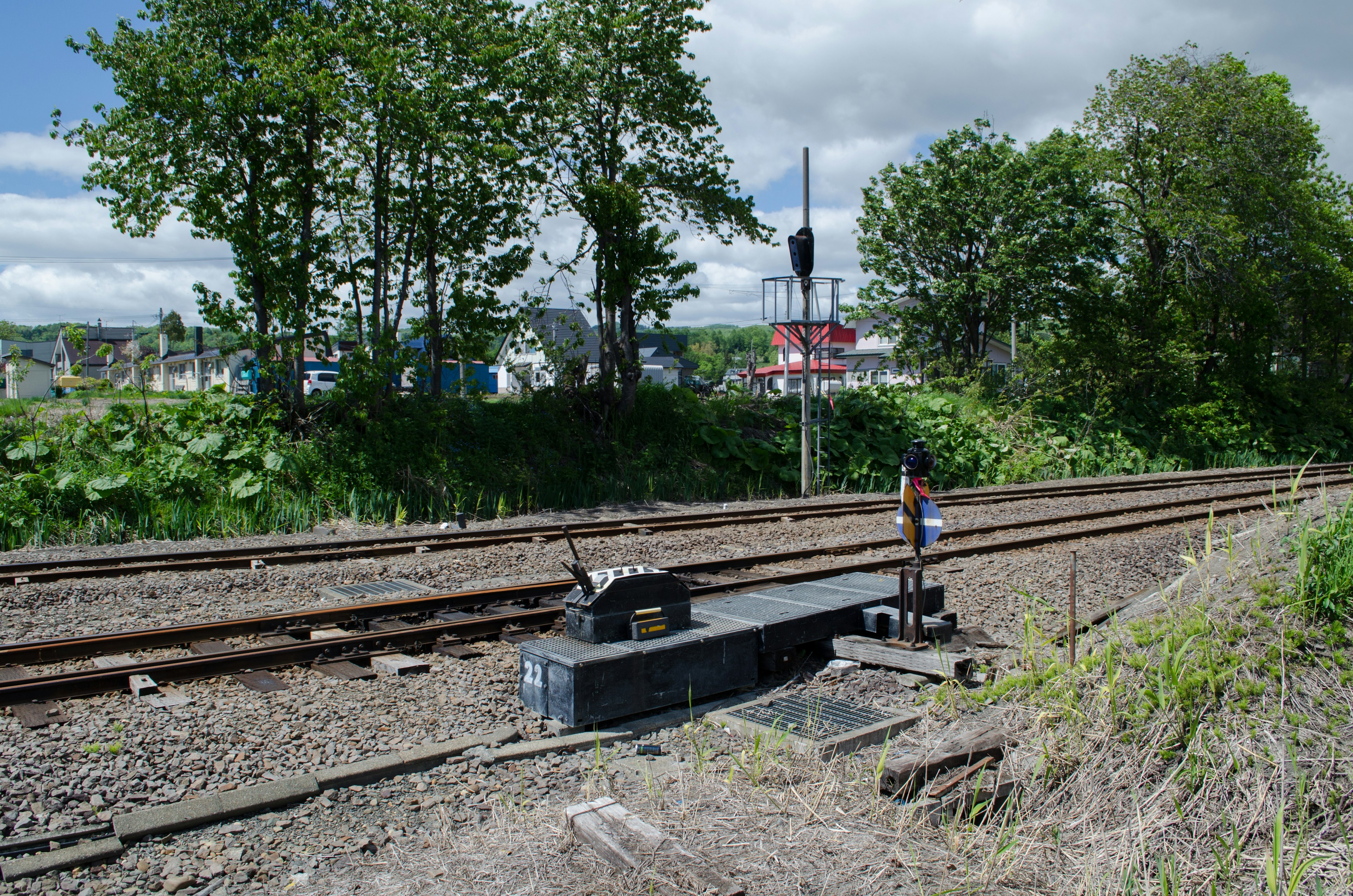 Malersicher Blick auf Bahngleise mit einem Signal und grünen Bäumen unter einem blauen Himmel