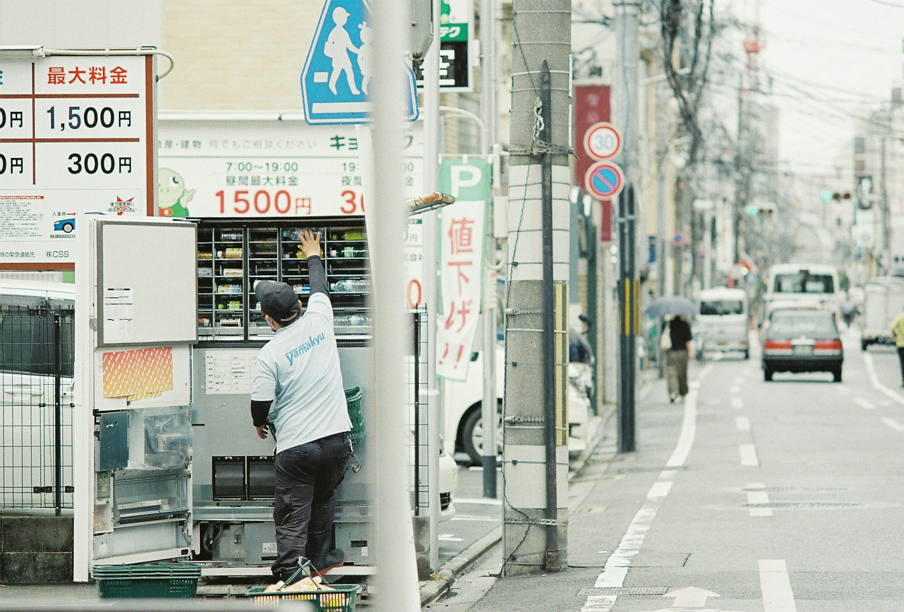 人が自動販売機の前で作業している街の風景