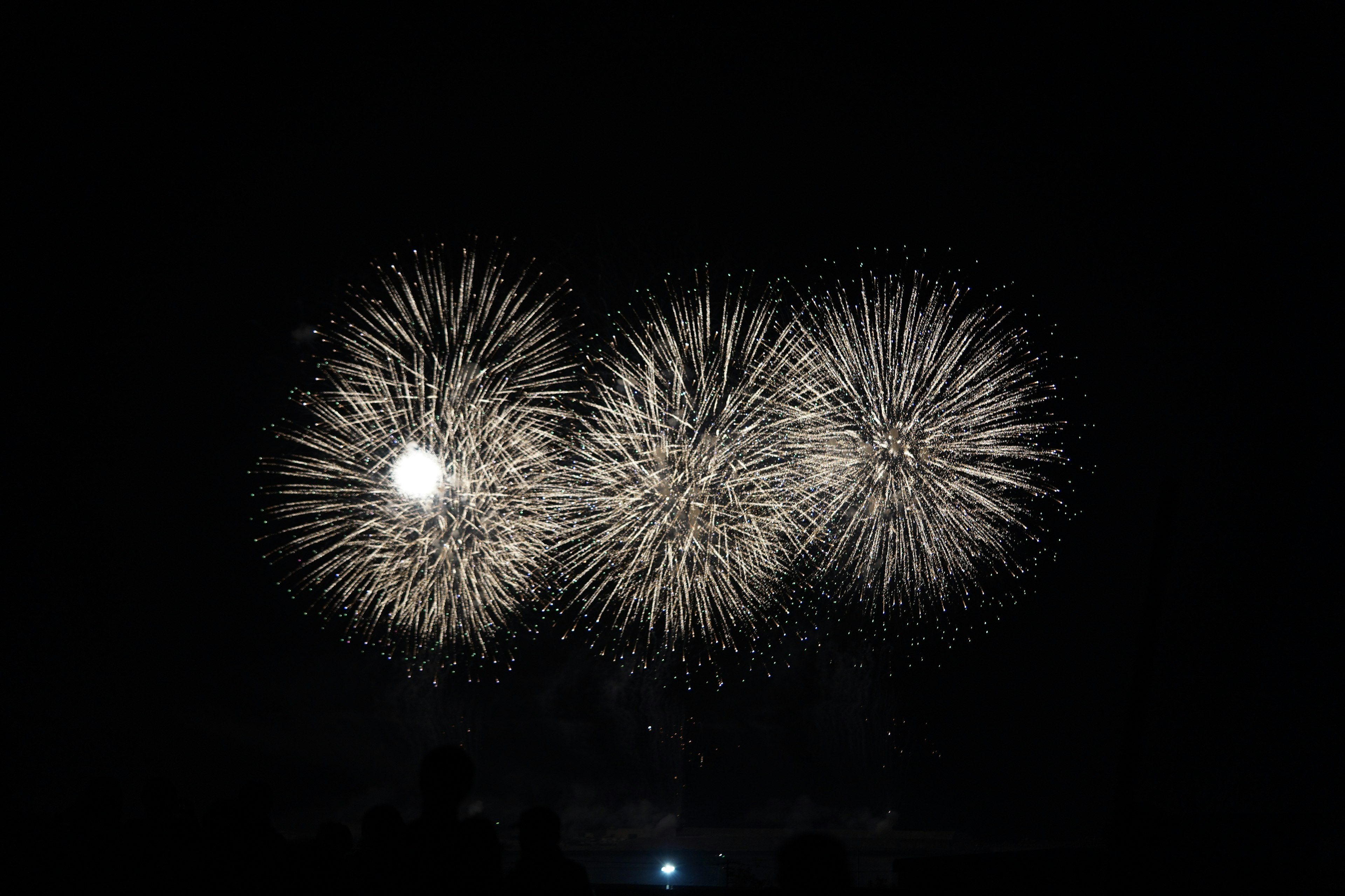 Espectáculo de fuegos artificiales blancos estallando en el cielo nocturno