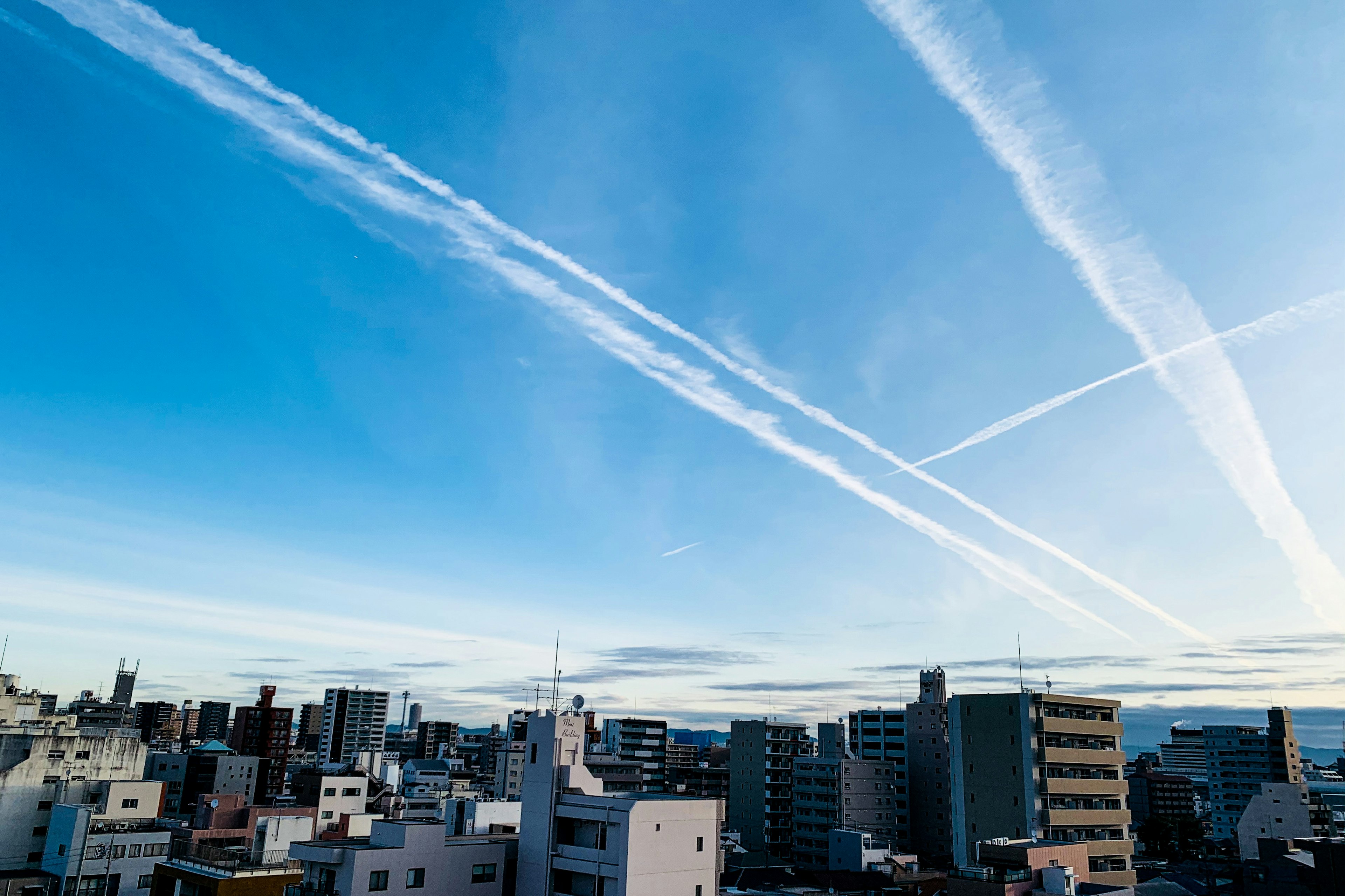 Stadtbild mit Flugzeugstreifen im blauen Himmel