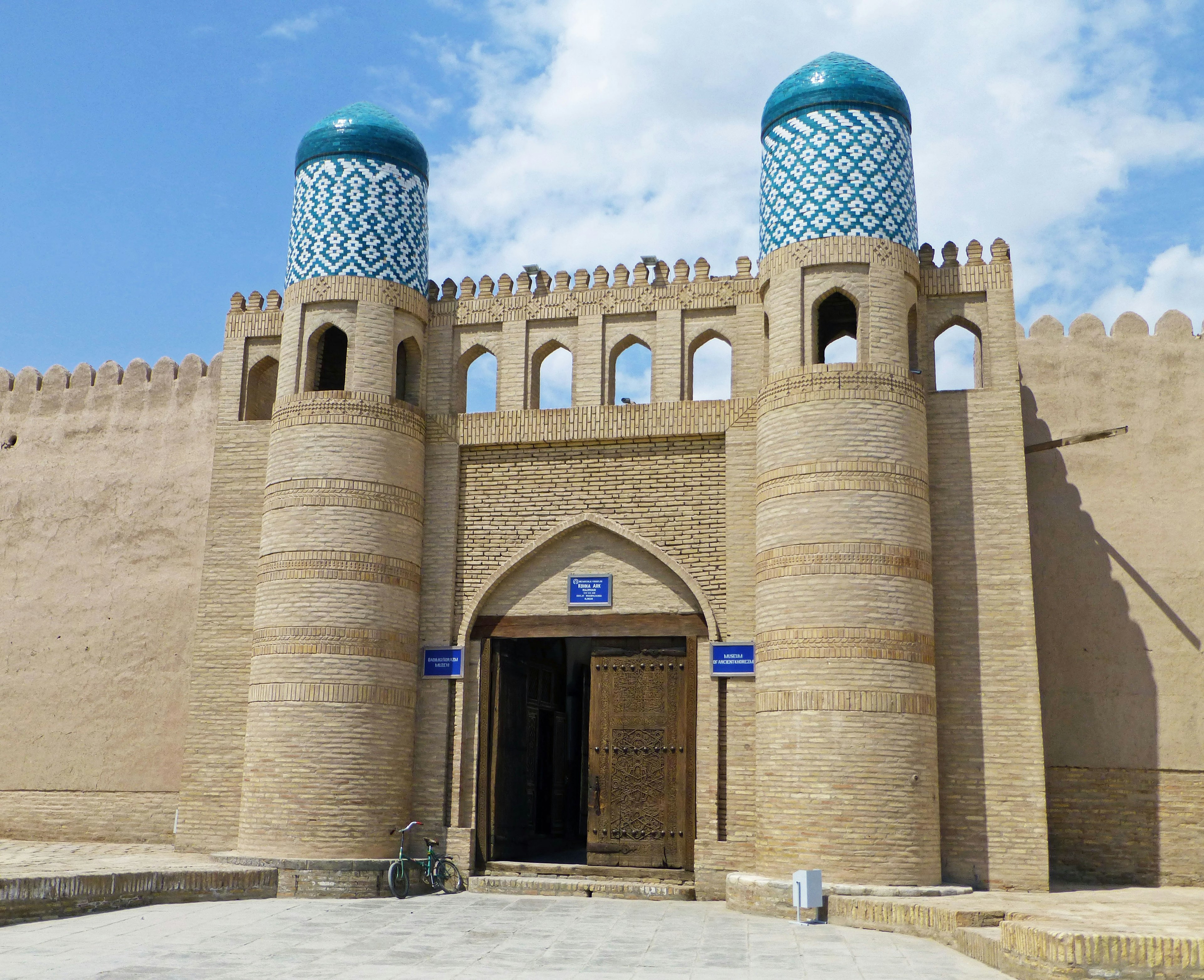 Entrada de un edificio histórico con cúpulas azules pequeñas torres en las paredes