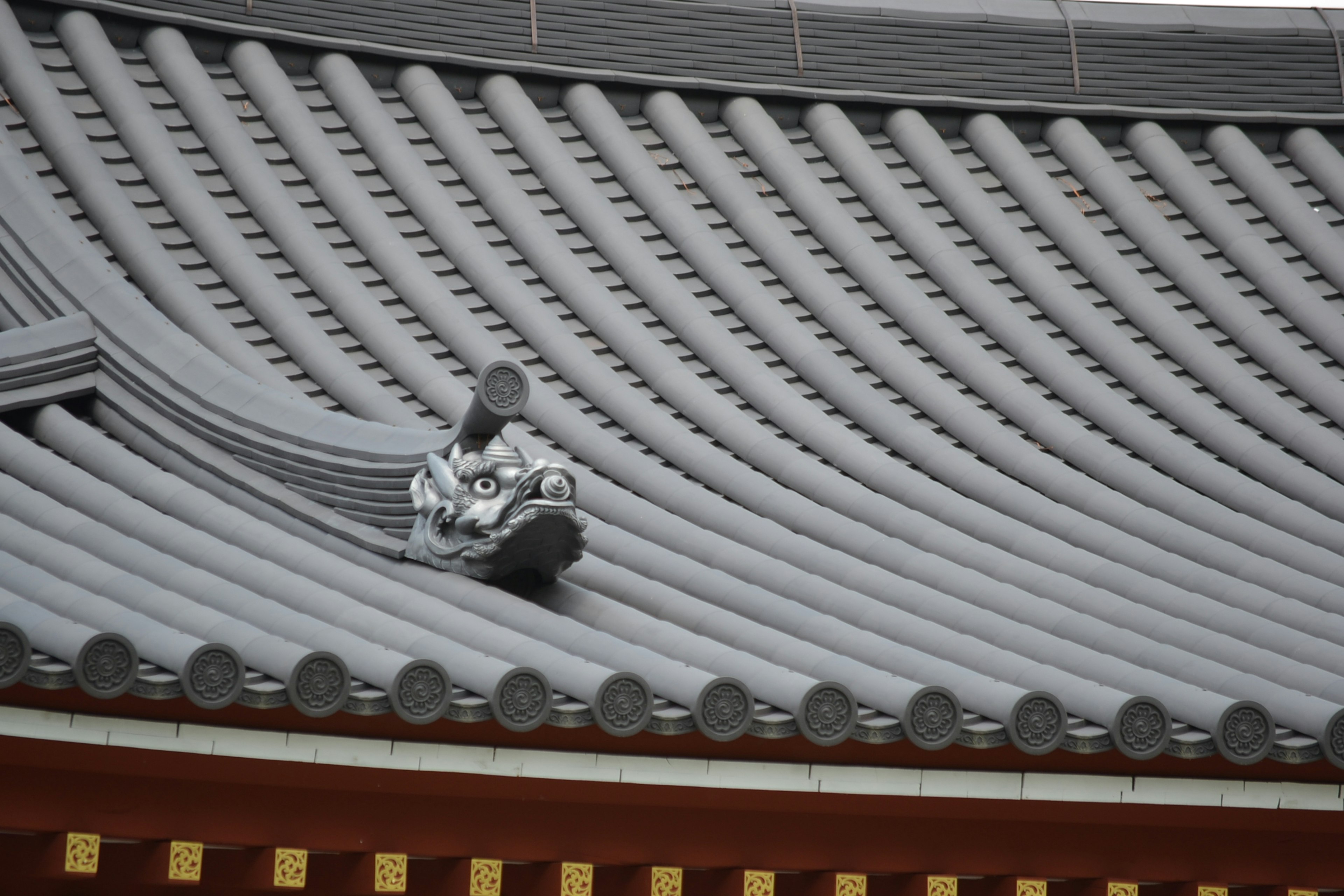 伝統的な日本の寺院の屋根、波状の瓦、装飾的な金色のトリム、中央に置かれた彫刻