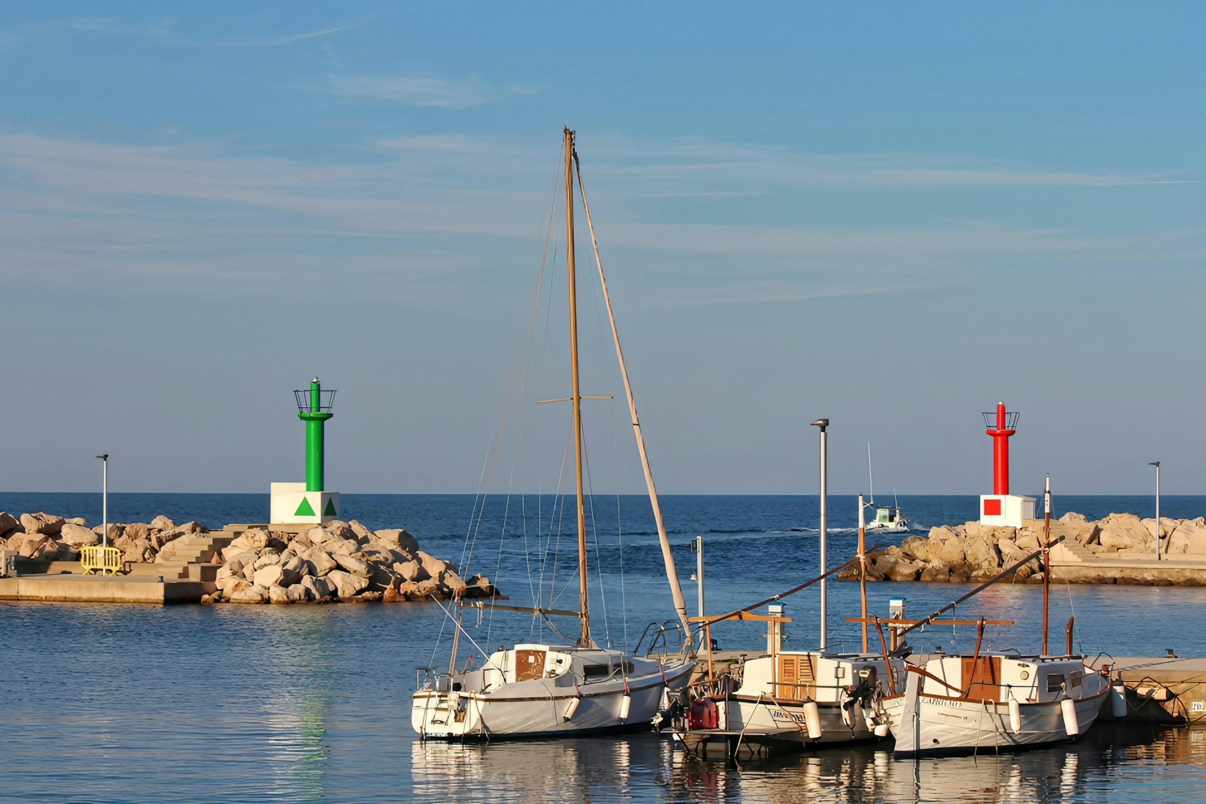 Barcos atracados en un puerto con faros rojos y verdes