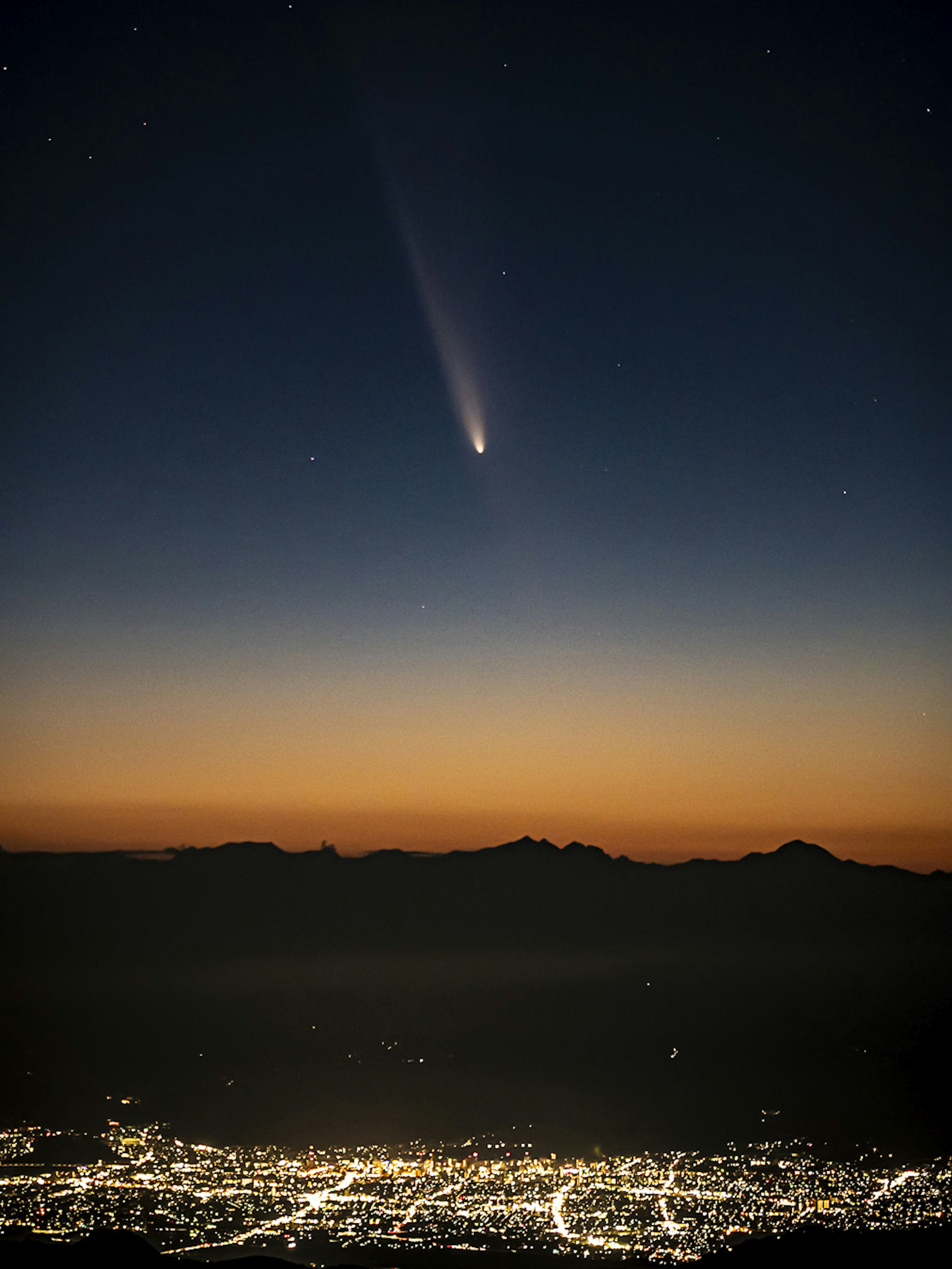 Cometa en el cielo nocturno sobre un paisaje urbano