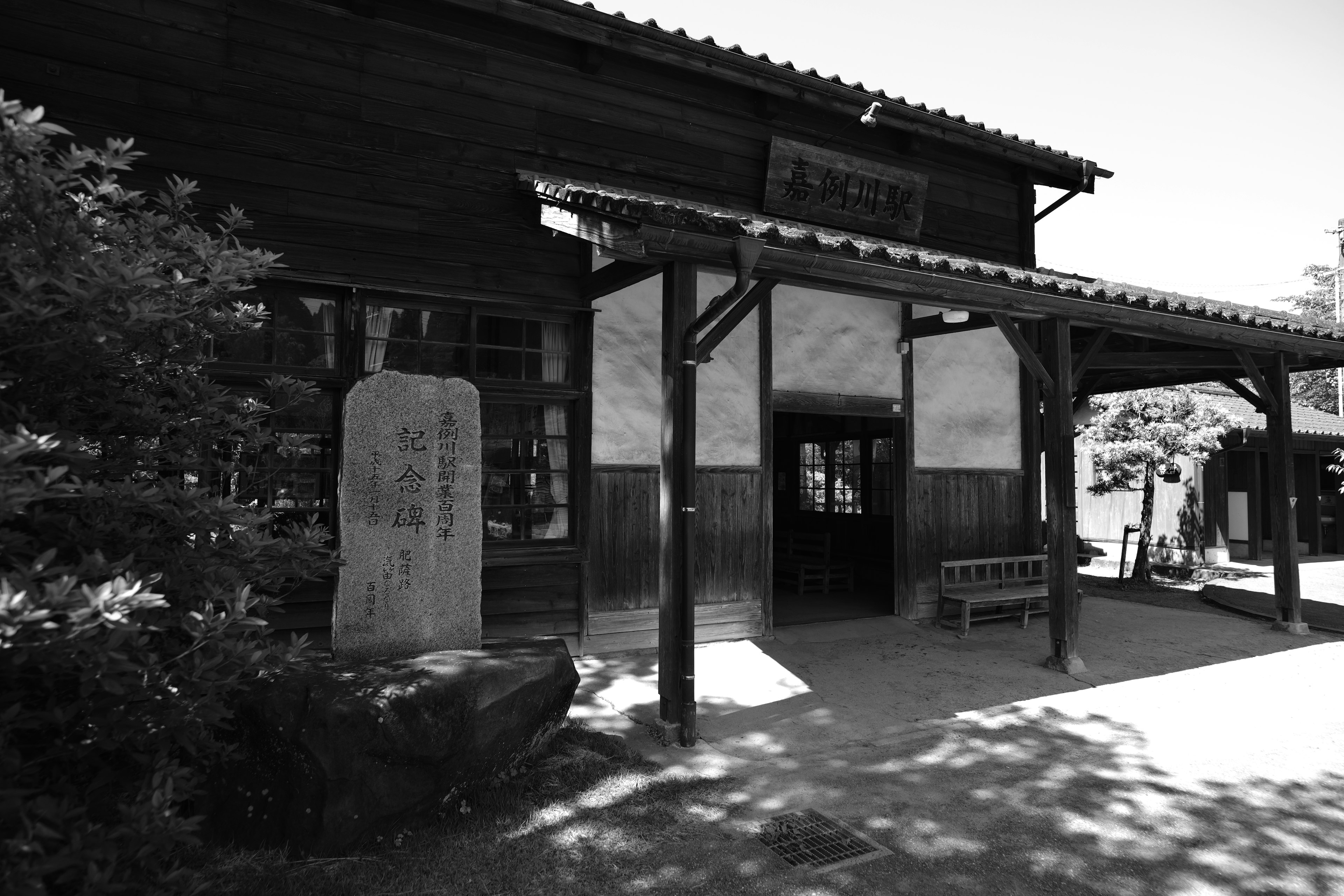 Exterior of a traditional wooden building with a stone monument