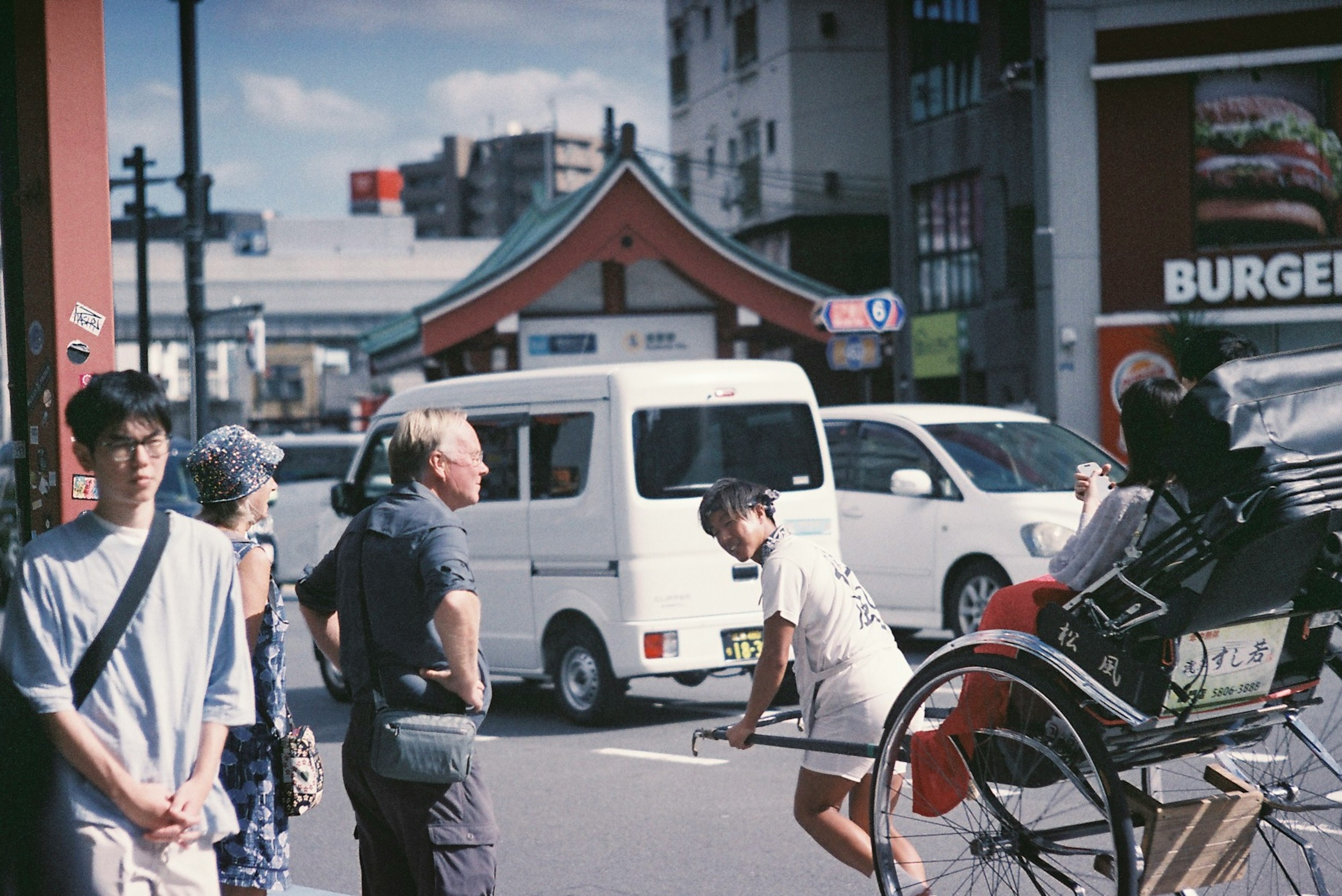 賑やかな街角で人々が行き交い人力車が停まっている風景