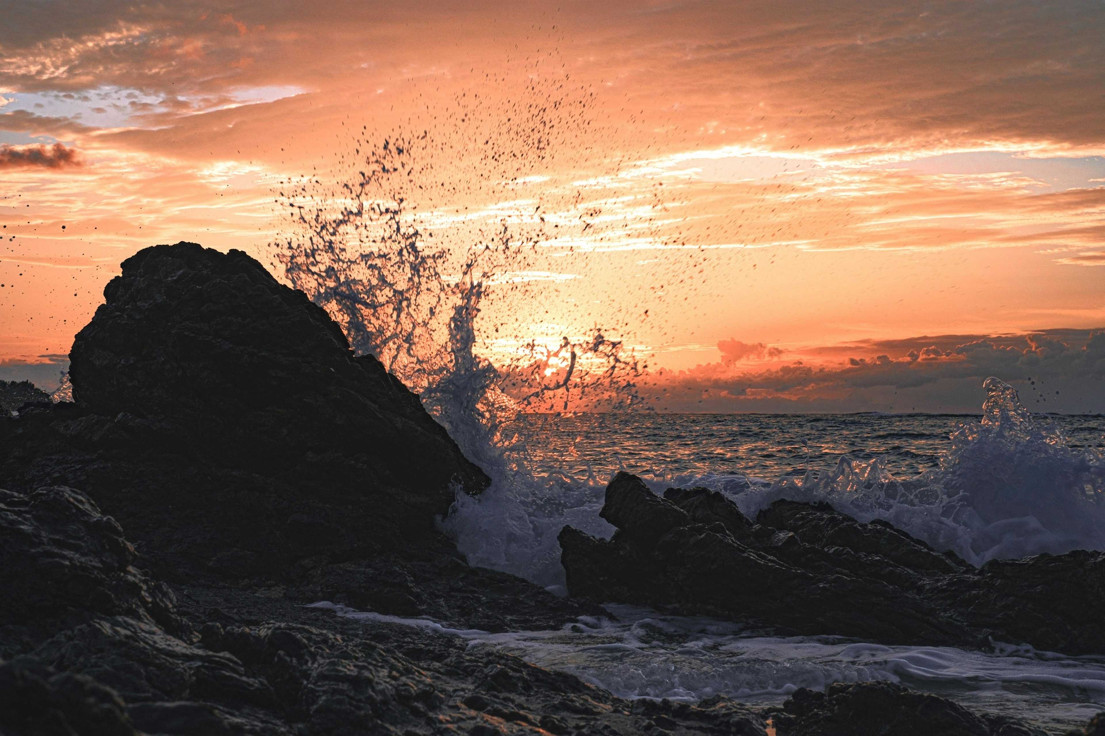 Hermoso paisaje marino al atardecer con olas rompiendo contra las rocas