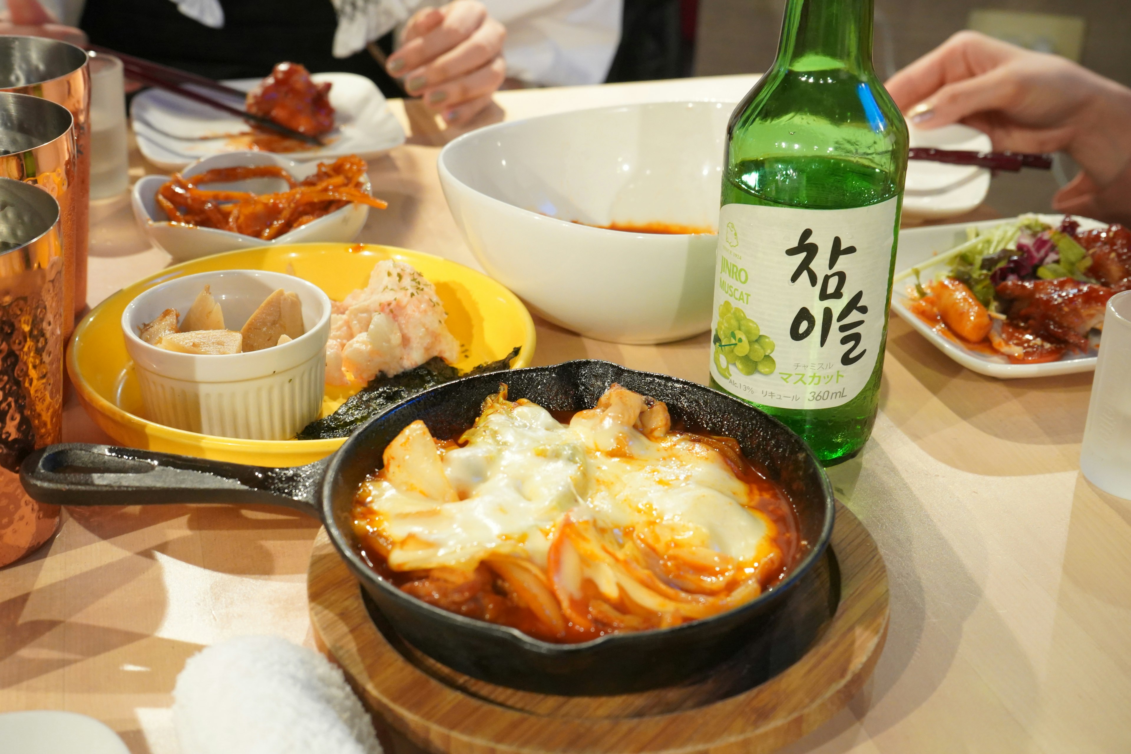 Table with Korean dishes and a bottle of soju