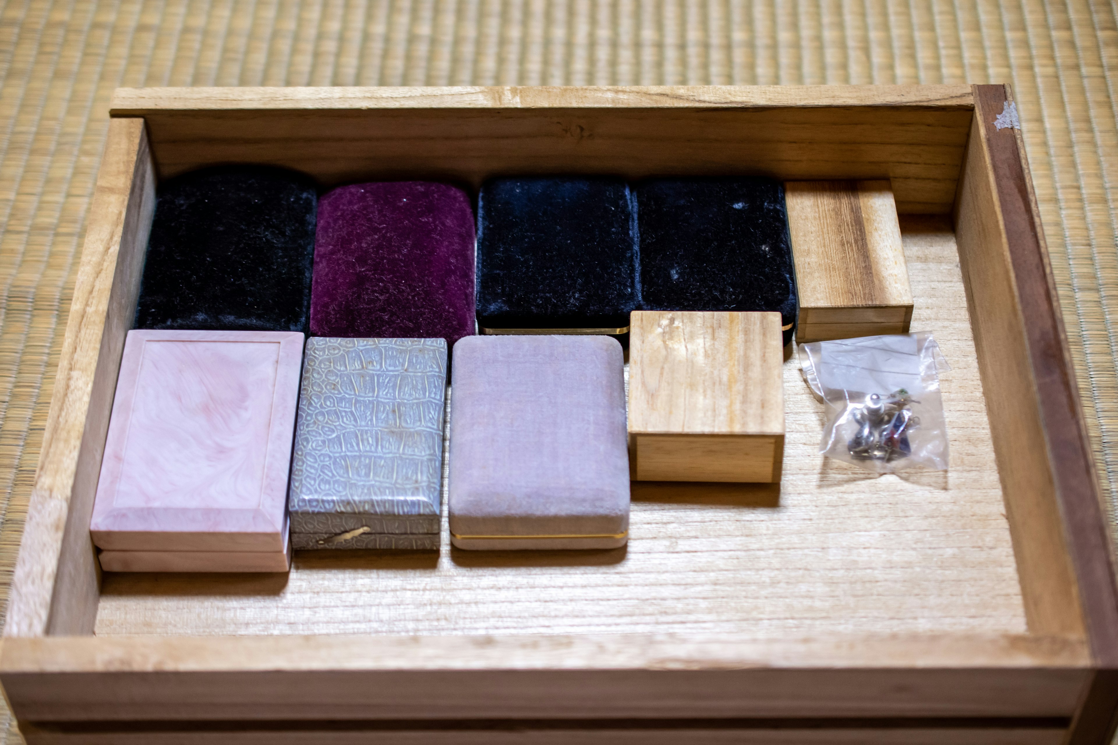 Un tiroir en bois contenant des boîtes en tissu de différentes couleurs et une petite boîte en bois