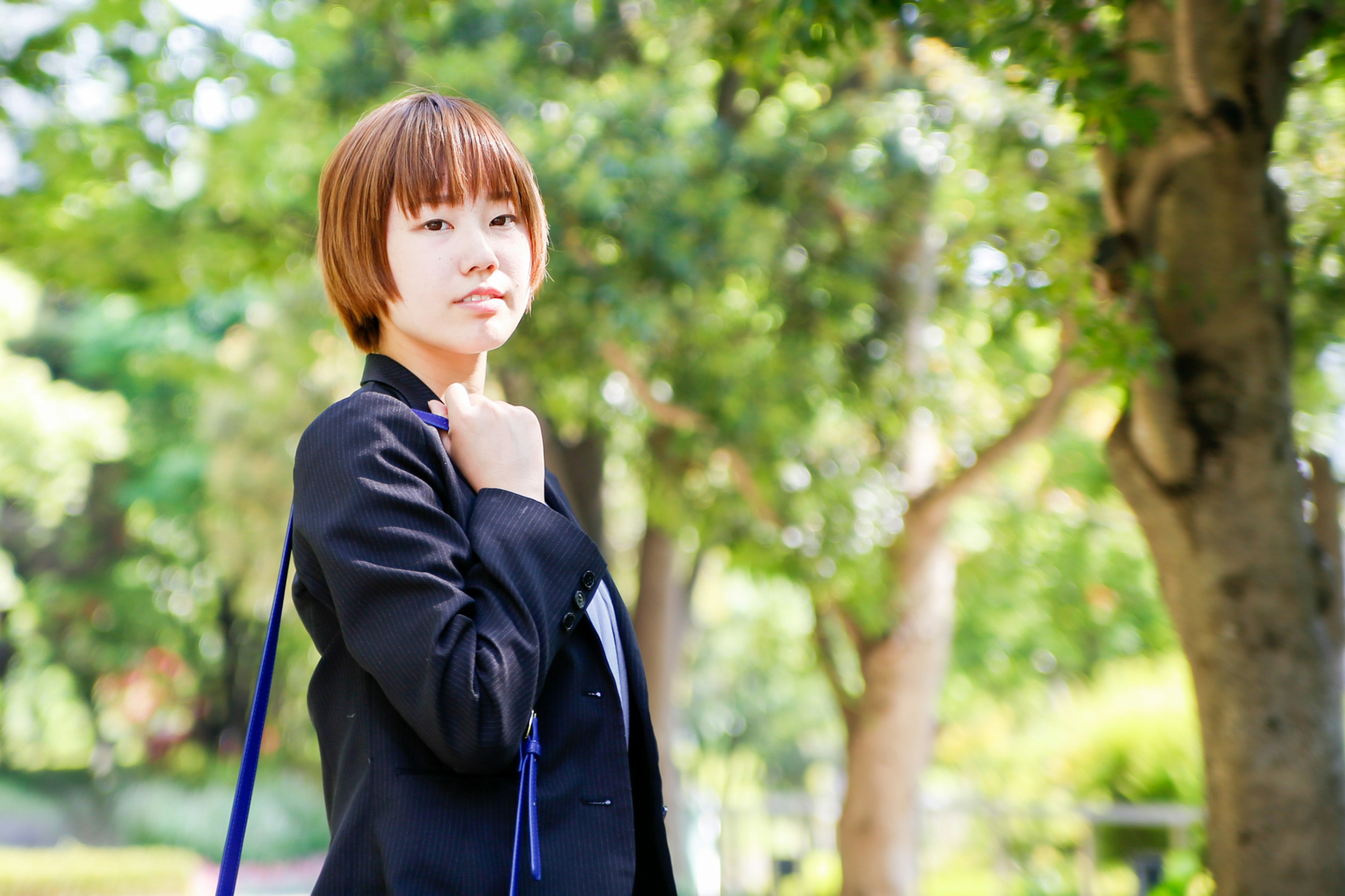 A woman in a black suit standing in a park