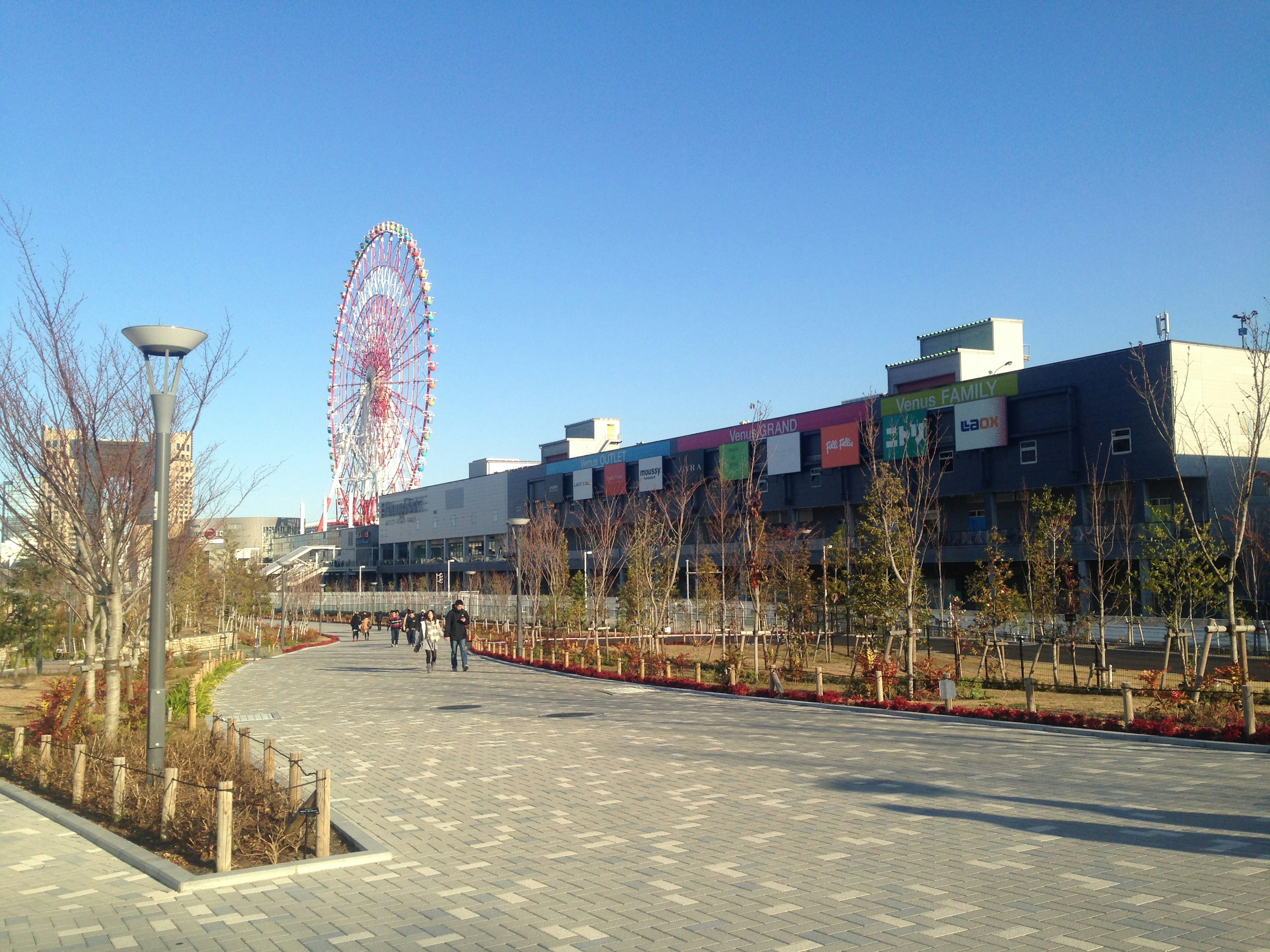 Pemandangan taman dengan roda ferris dan bangunan modern