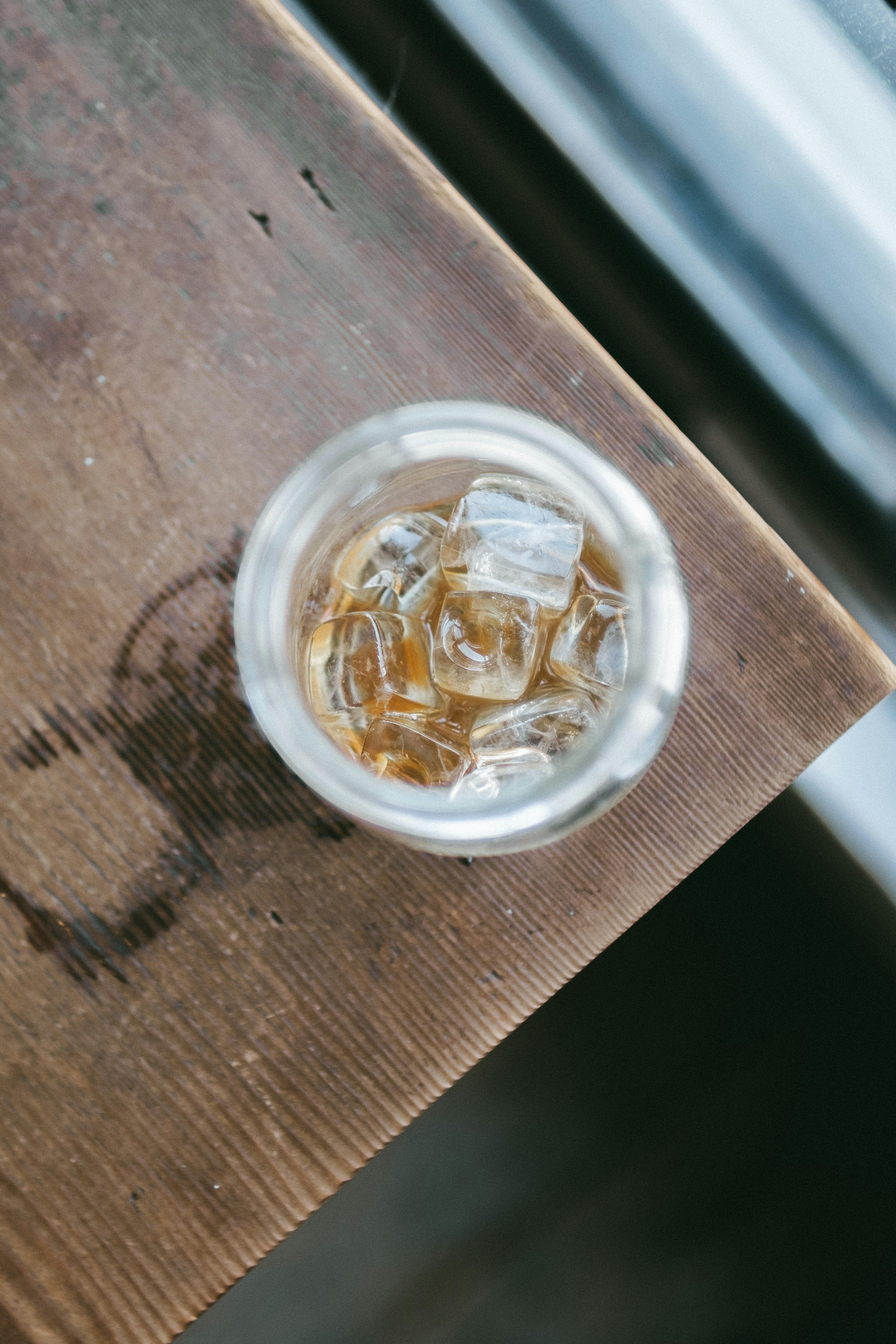 A clear glass with ice containing a brown beverage