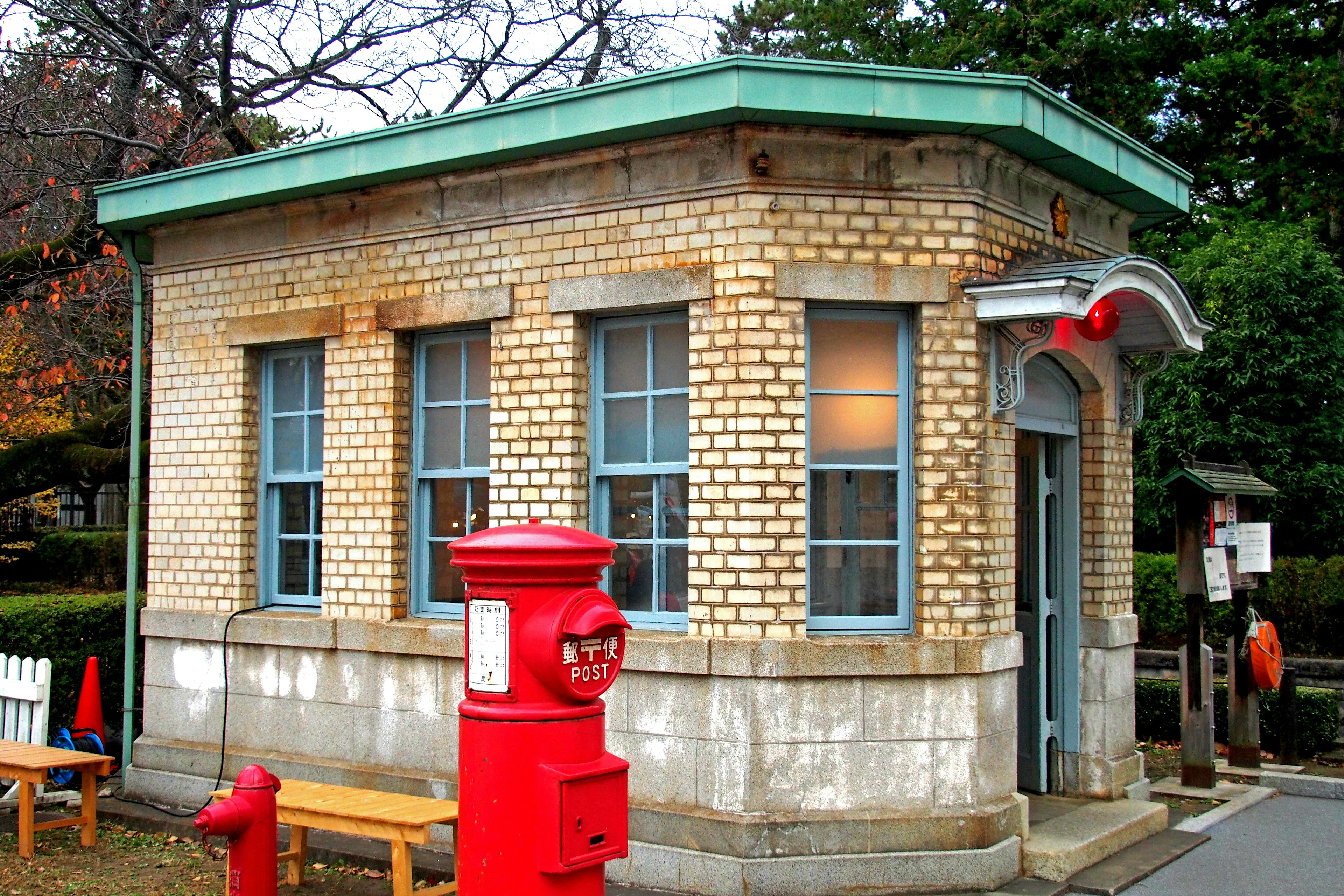 Pequeño edificio de correos de ladrillo con un buzón rojo distintivo