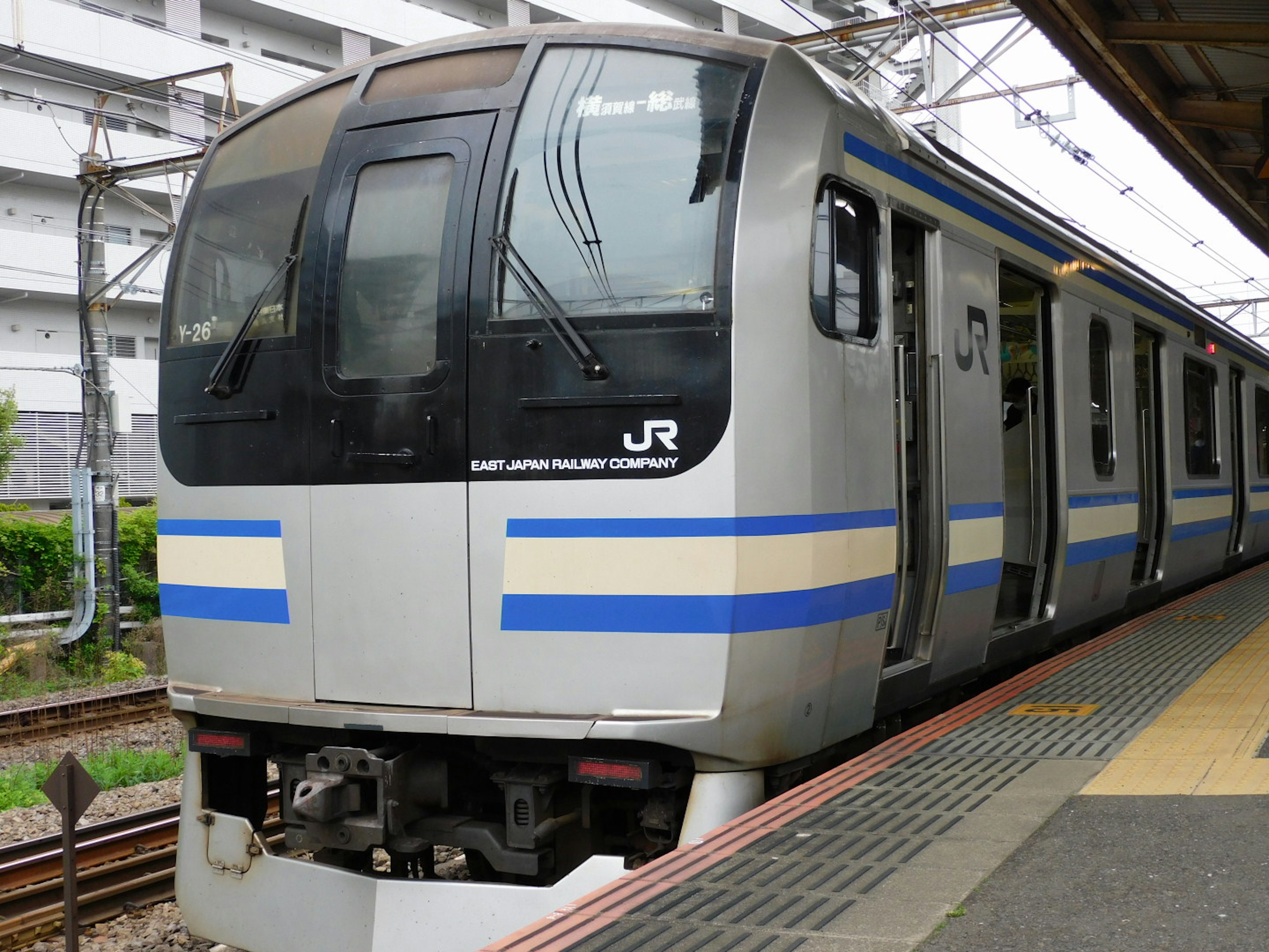 青いストライプの入った銀色の電車が駅に停車している