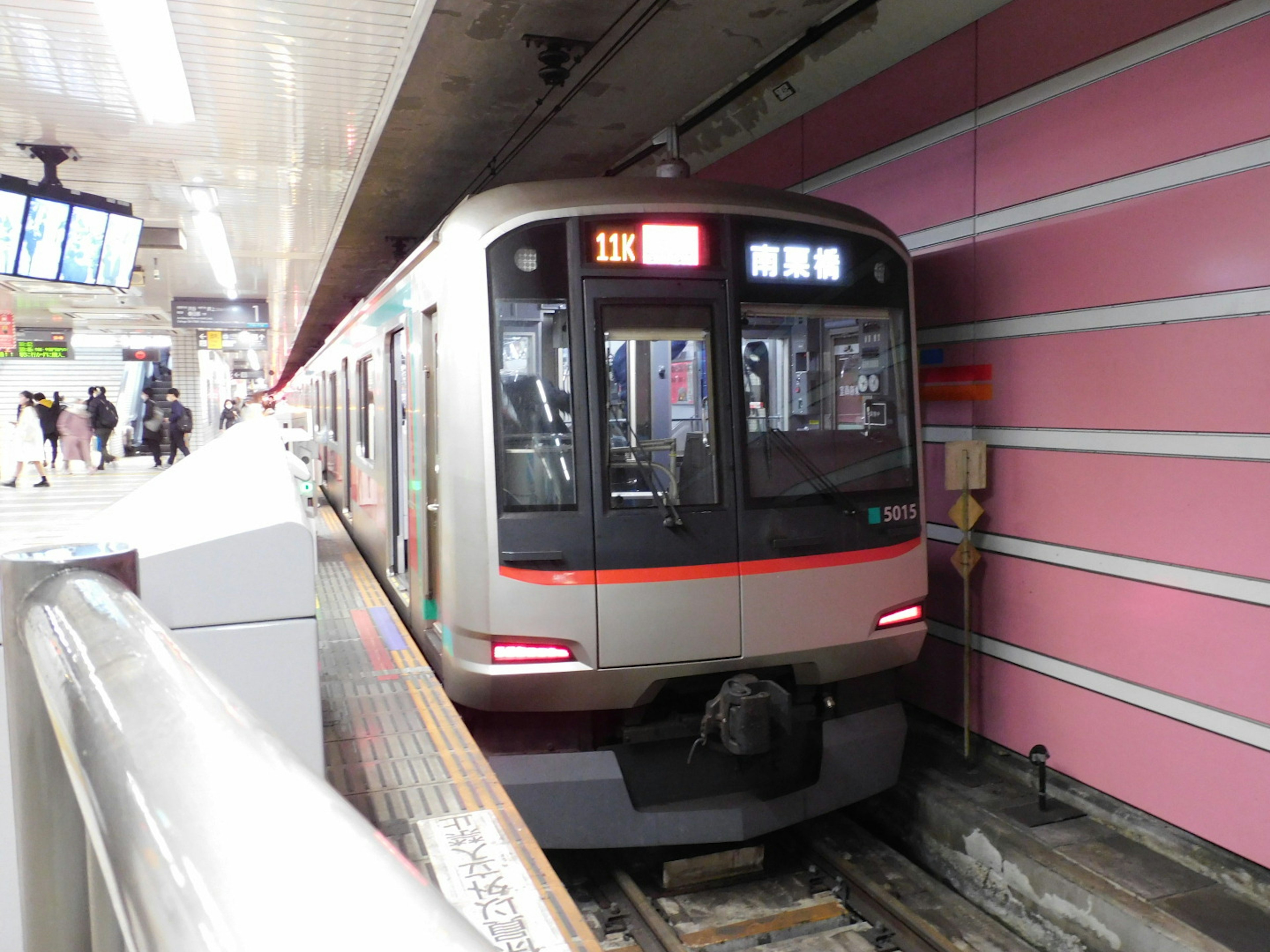 駅に停車中の電車とピンクの壁