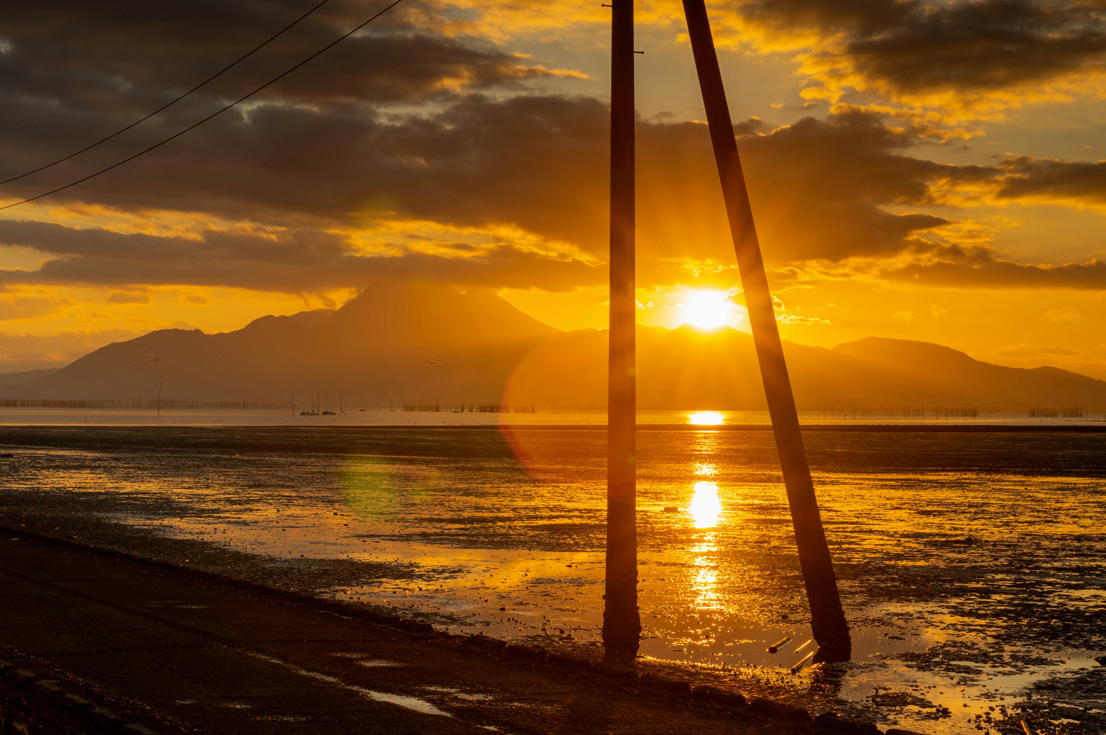 夕日が山の後ろに沈む風景に立つ2本の柱