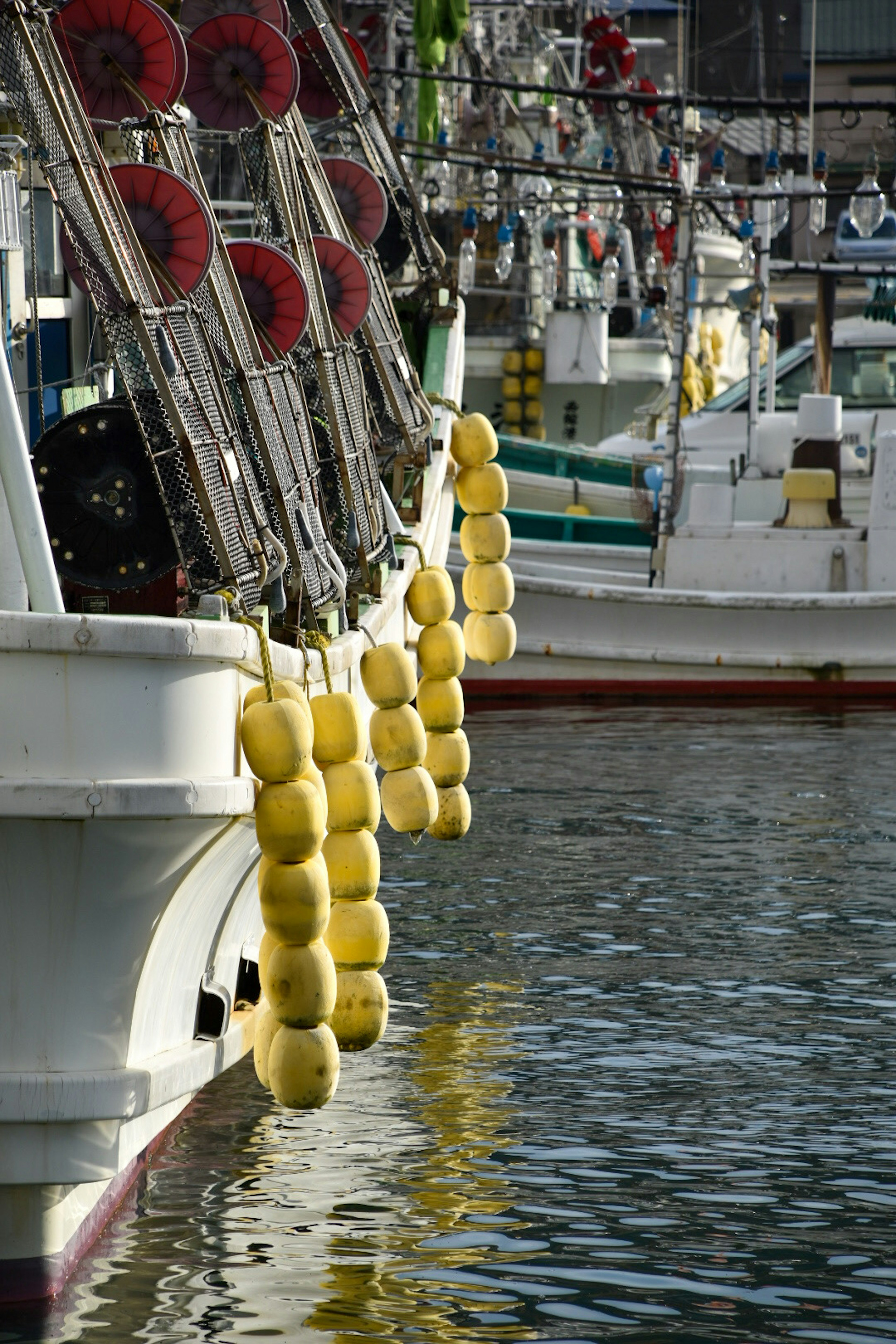 Yellow buoys hanging from the side of fishing boats in the harbor