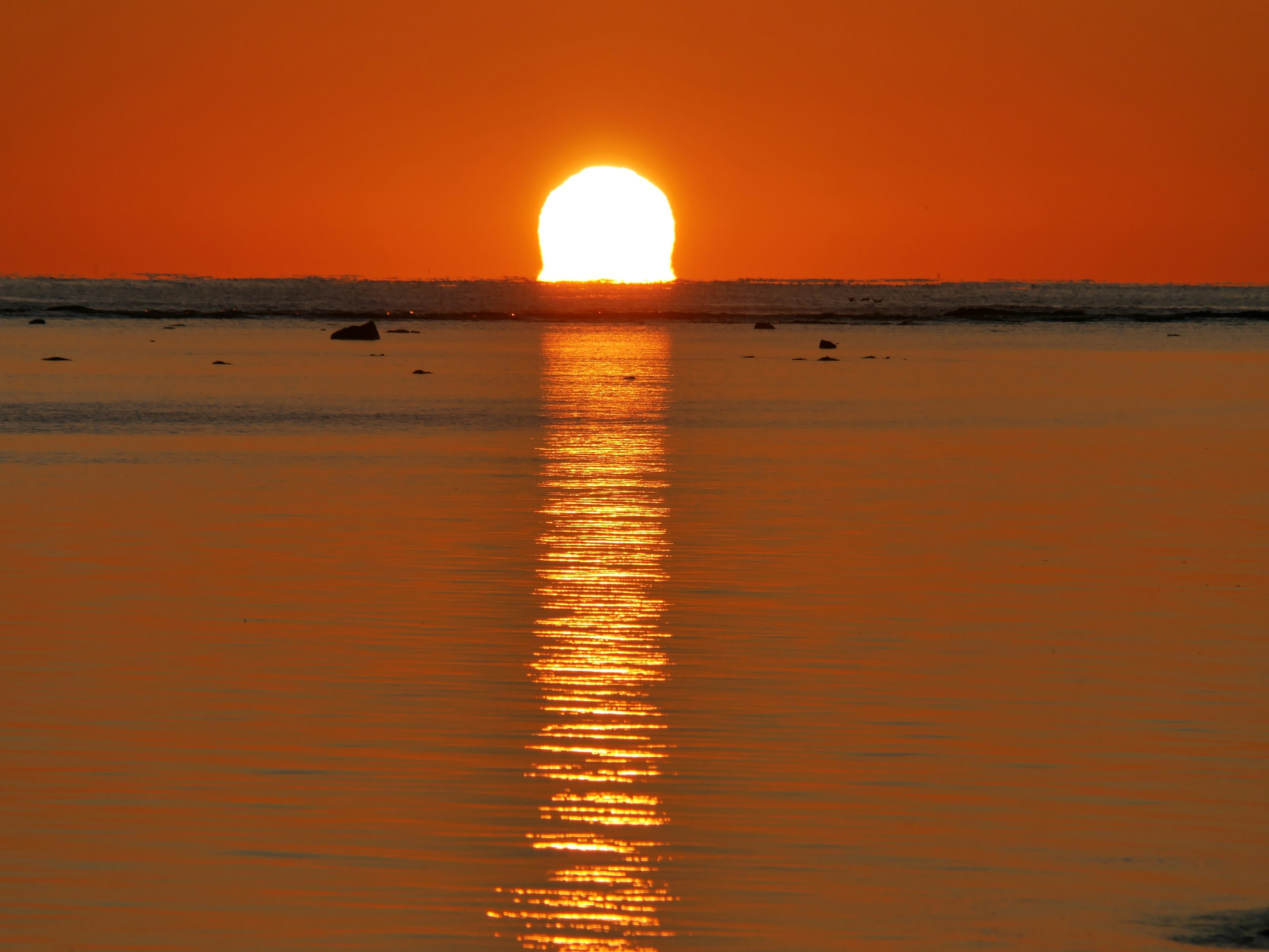 オレンジ色の夕日が海に沈む美しい光景