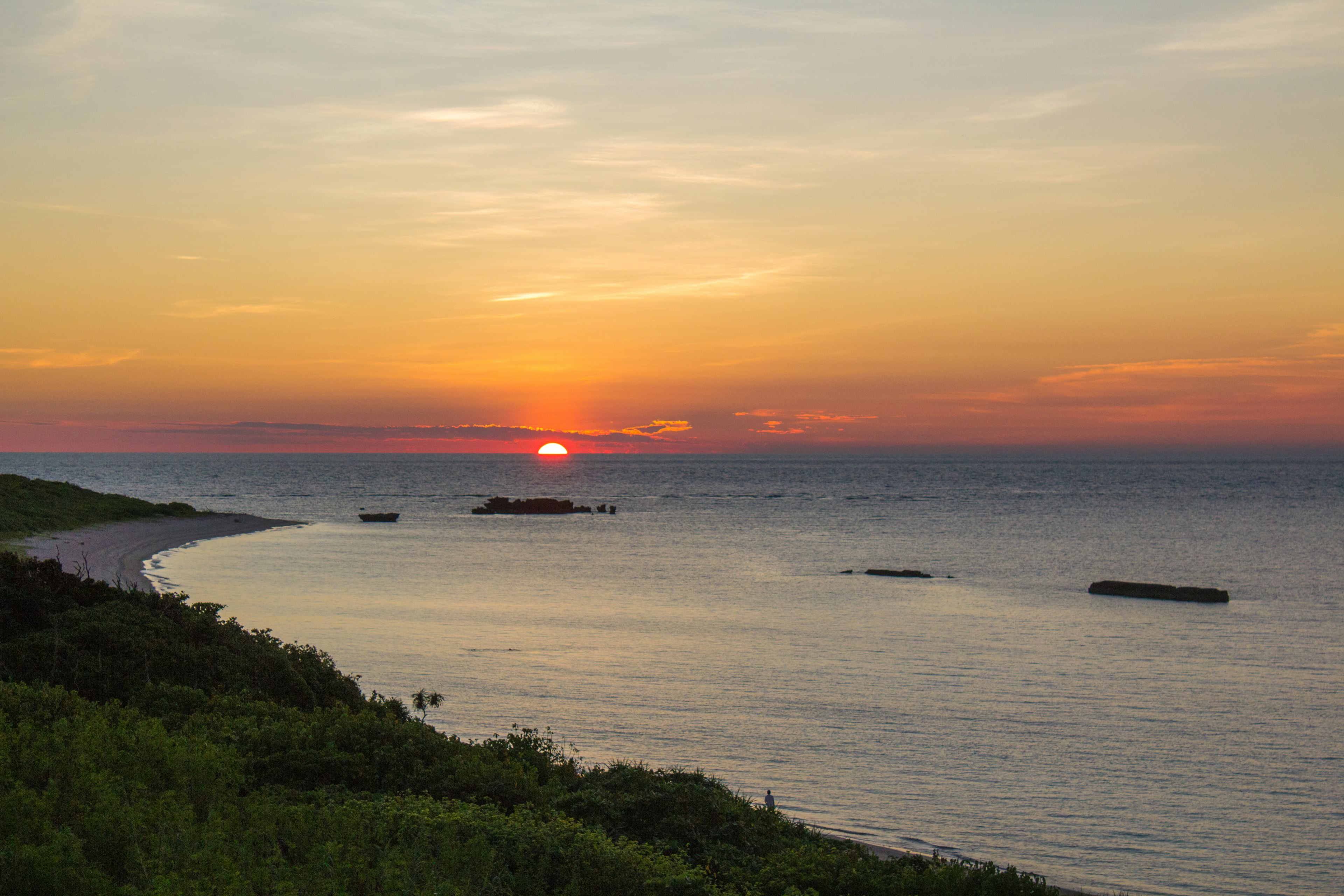 美丽的日落海景，绿意盎然的海岸线和温柔的波浪