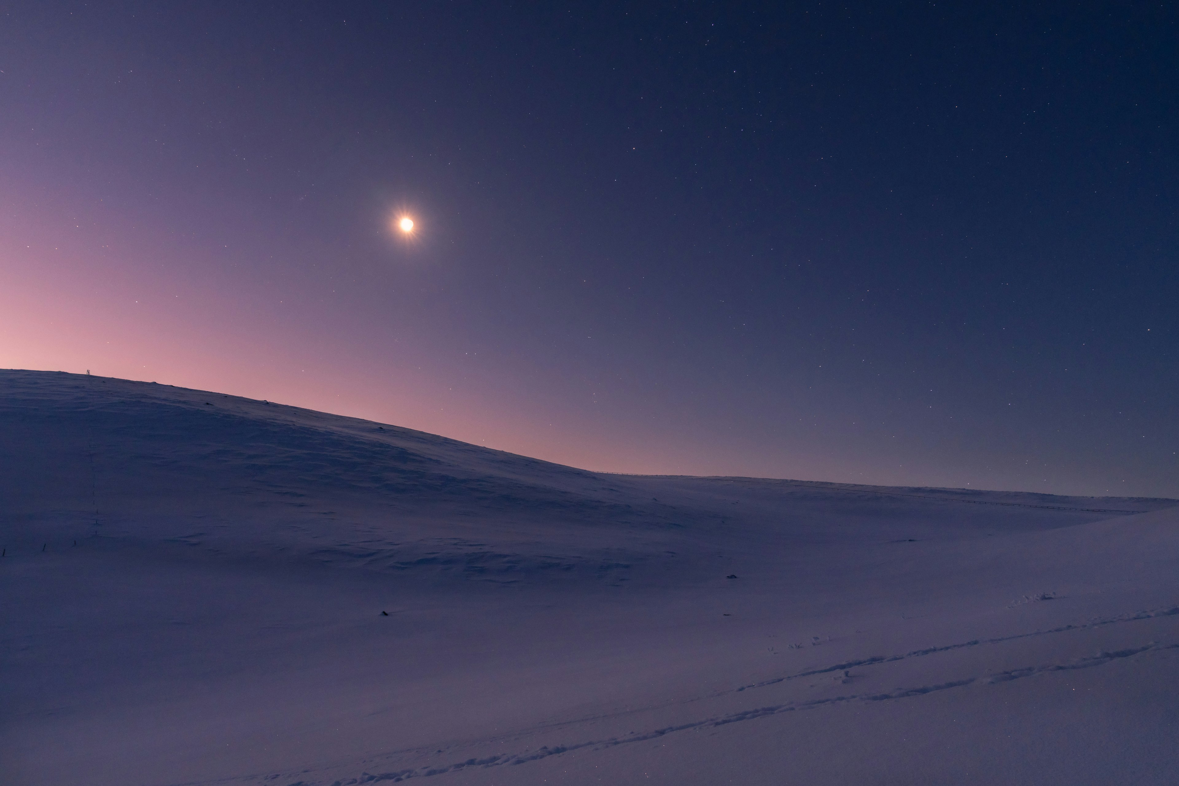 Vasto paesaggio innevato illuminato dalla luce della luna e dal cielo stellato