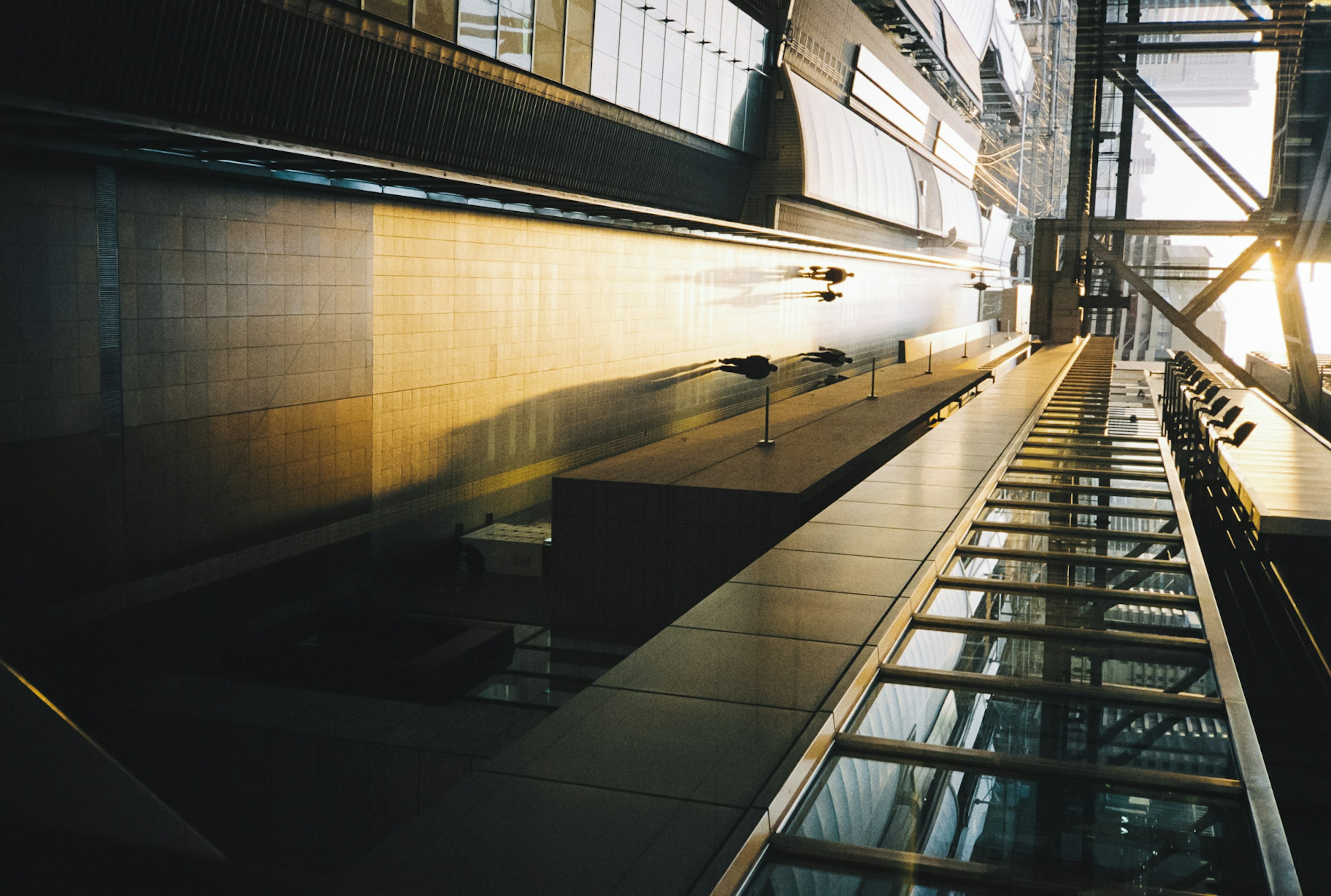 Vista diagonal del interior de un gran edificio mostrando elementos estructurales y reflejos de luz