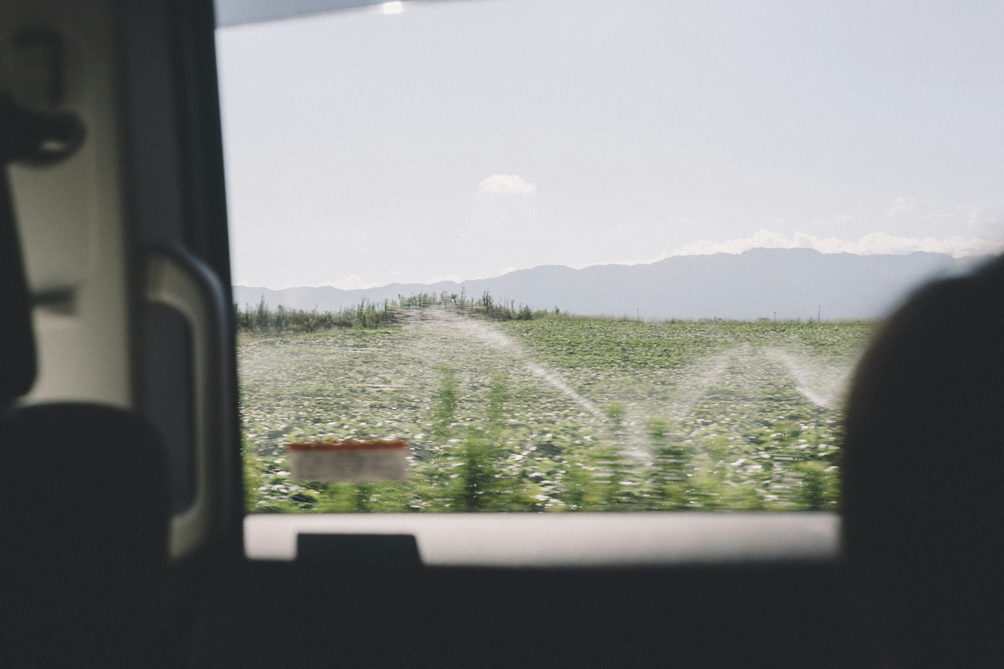 Amplio paisaje agrícola con aspersores visibles desde una ventana de coche