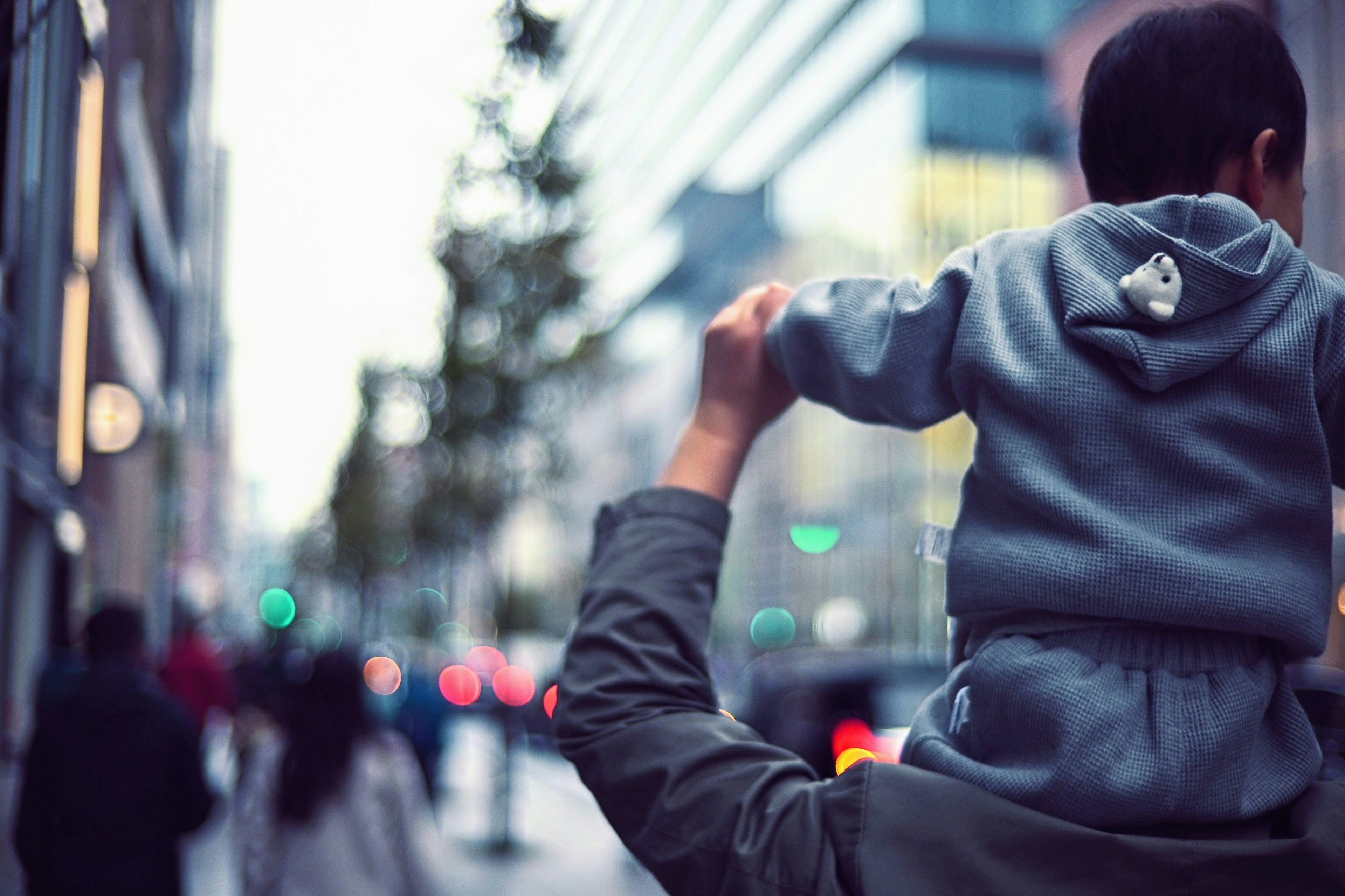 A father carrying a child on his shoulders in a city street evening scene