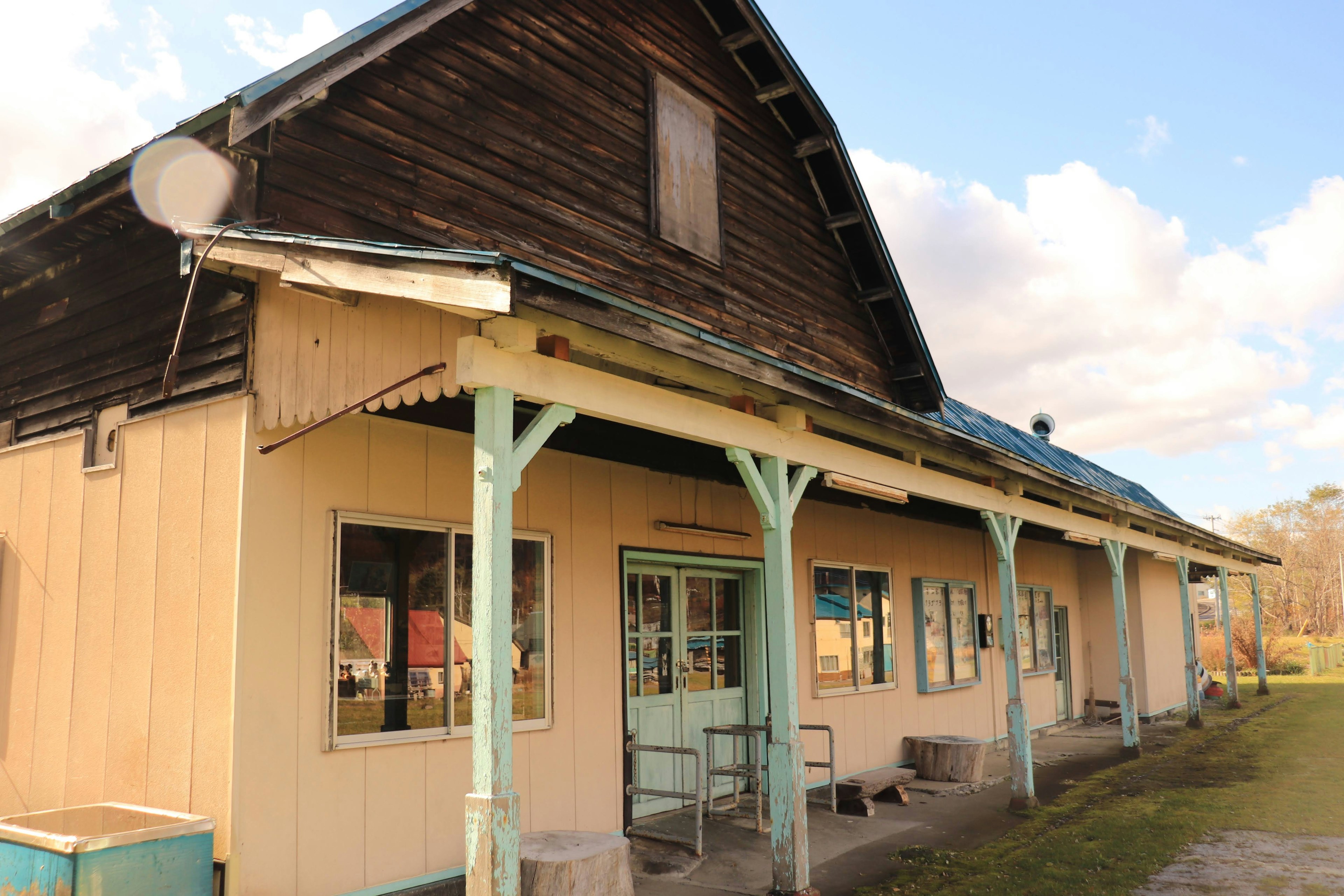 Exterior of an old building with a wooden roof blue columns and multiple windows