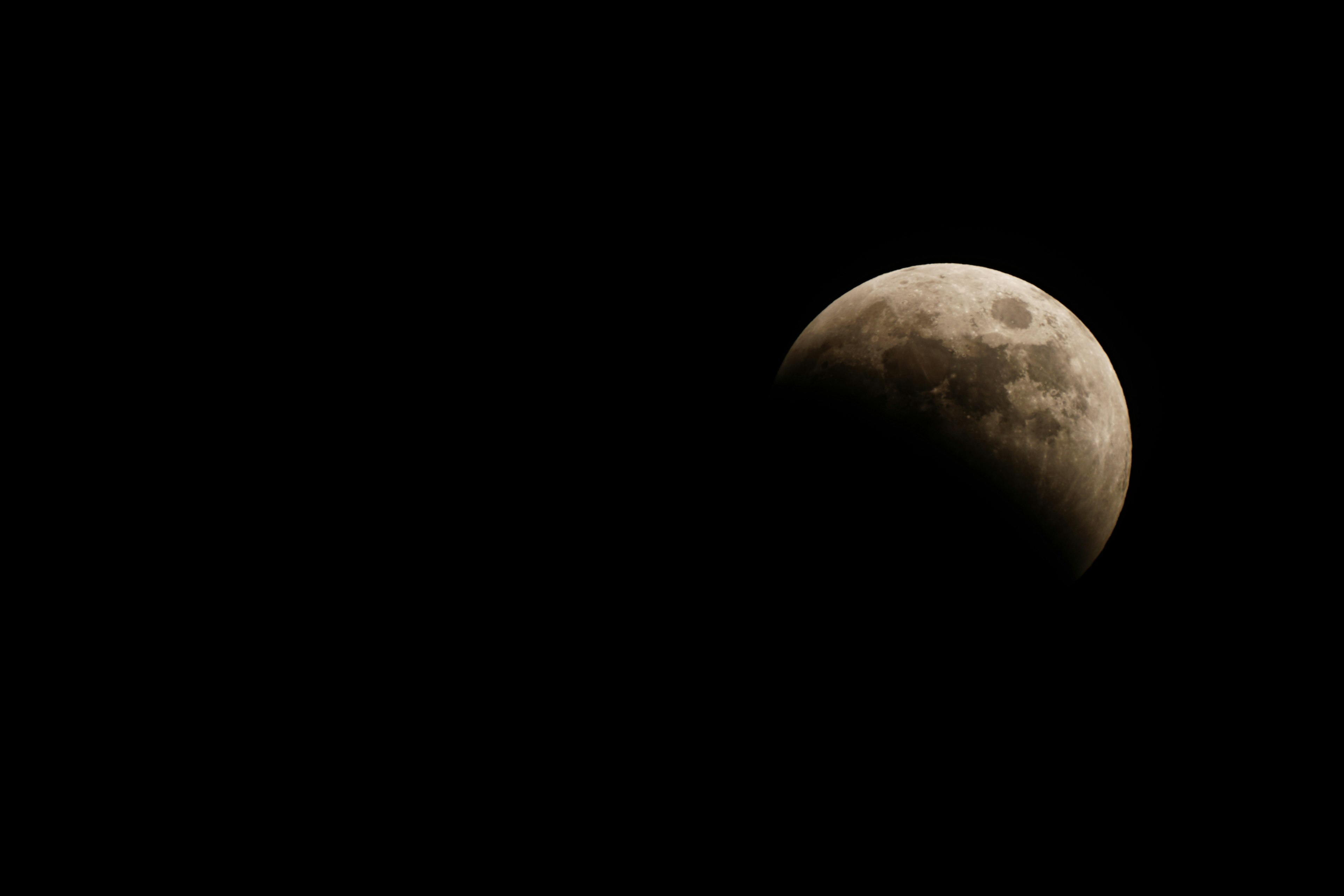 Kedekatan bulan yang sebagian diterangi di latar belakang gelap