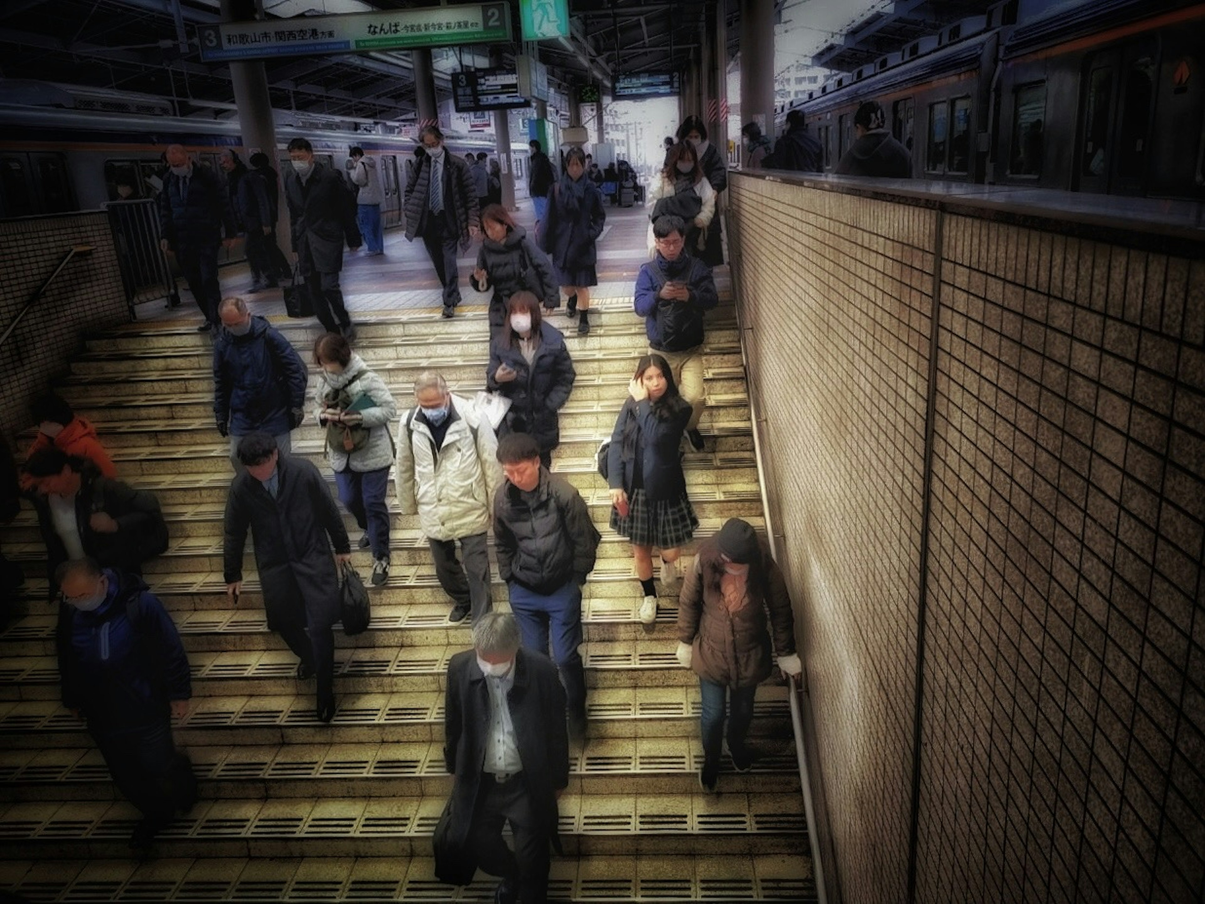 Folla di pendolari che scende le scale in una stazione