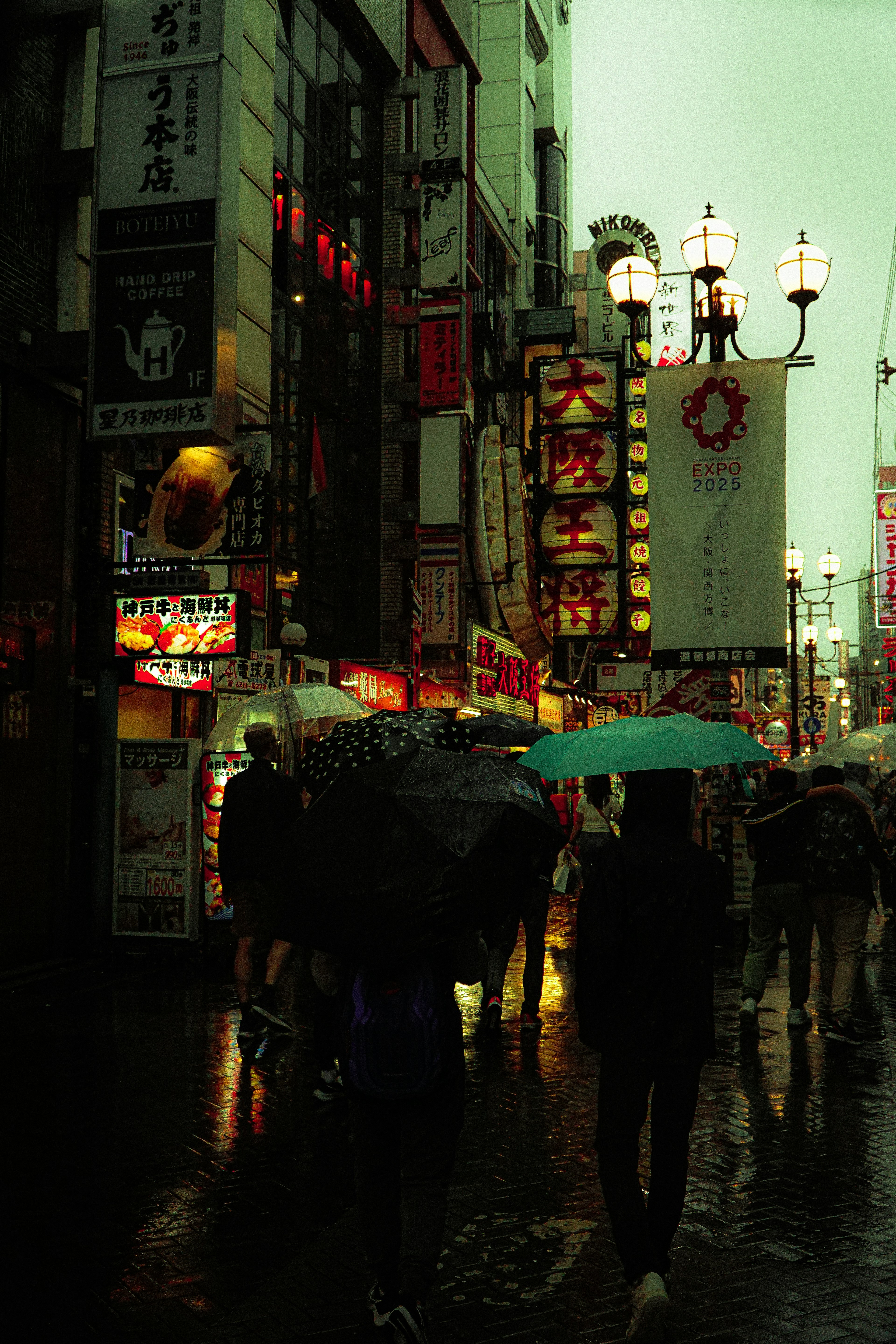 Busy urban street in the rain with people holding umbrellas neon signs illuminating the scene