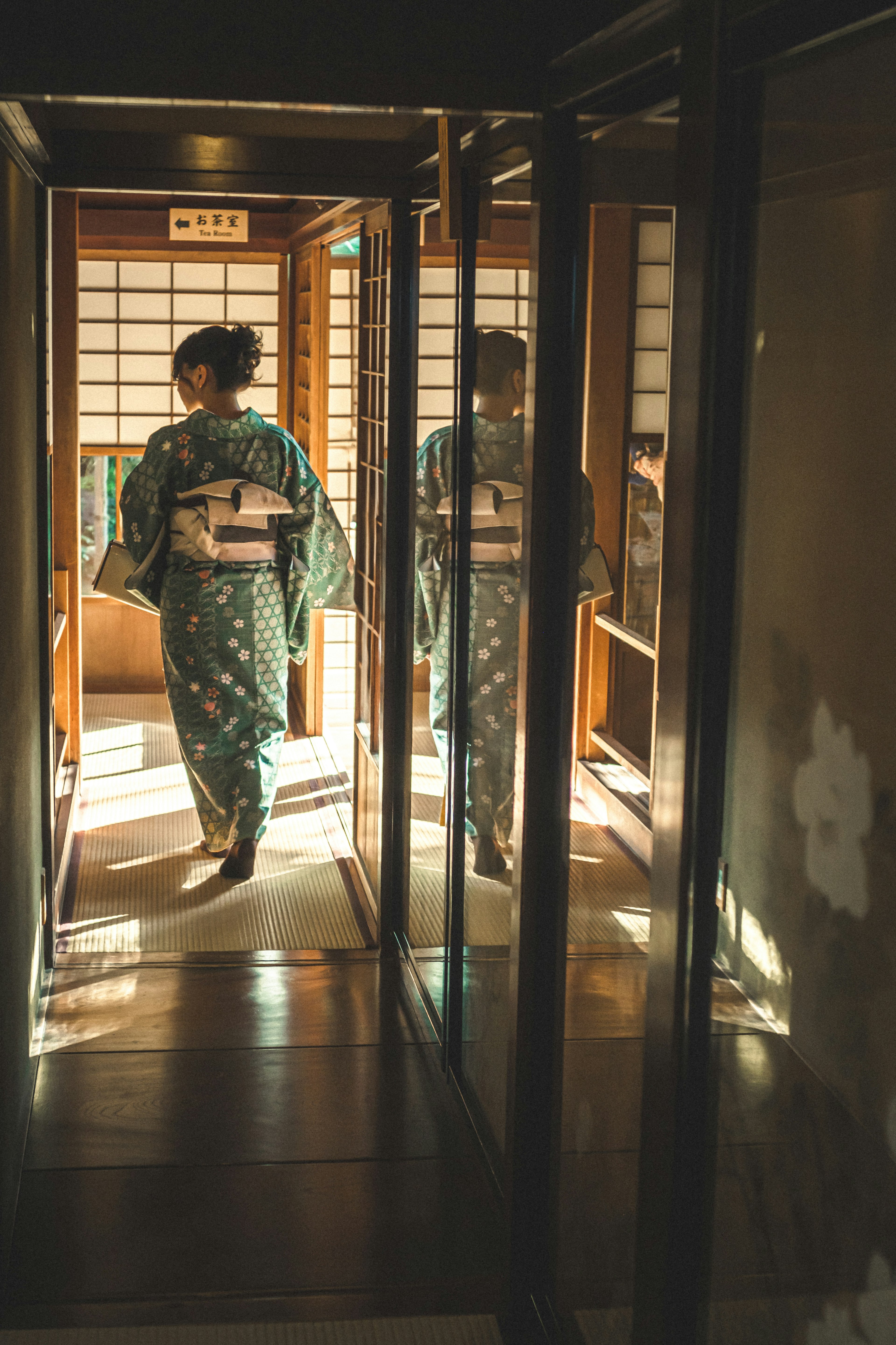 Two women dressed in kimono walking through a hallway